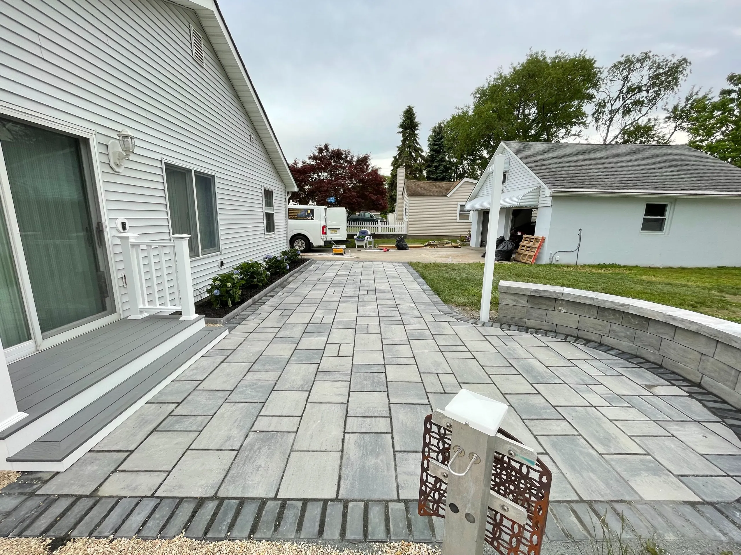After: the finished paver layout, rear entry steps and curved wall beside the lawn.