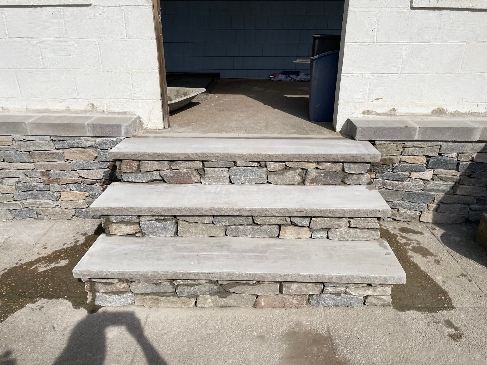 After: light-gray slab treads and stone-faced risers at the rebuilt entrance steps.
