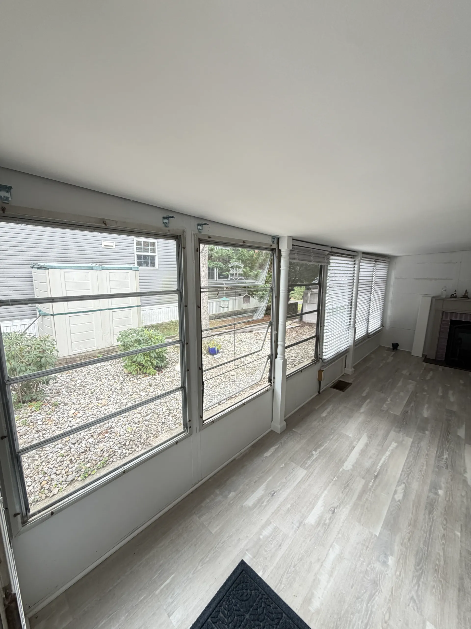 Before: the sunroom window wall, lower panels and fireplace end before the interior refresh.