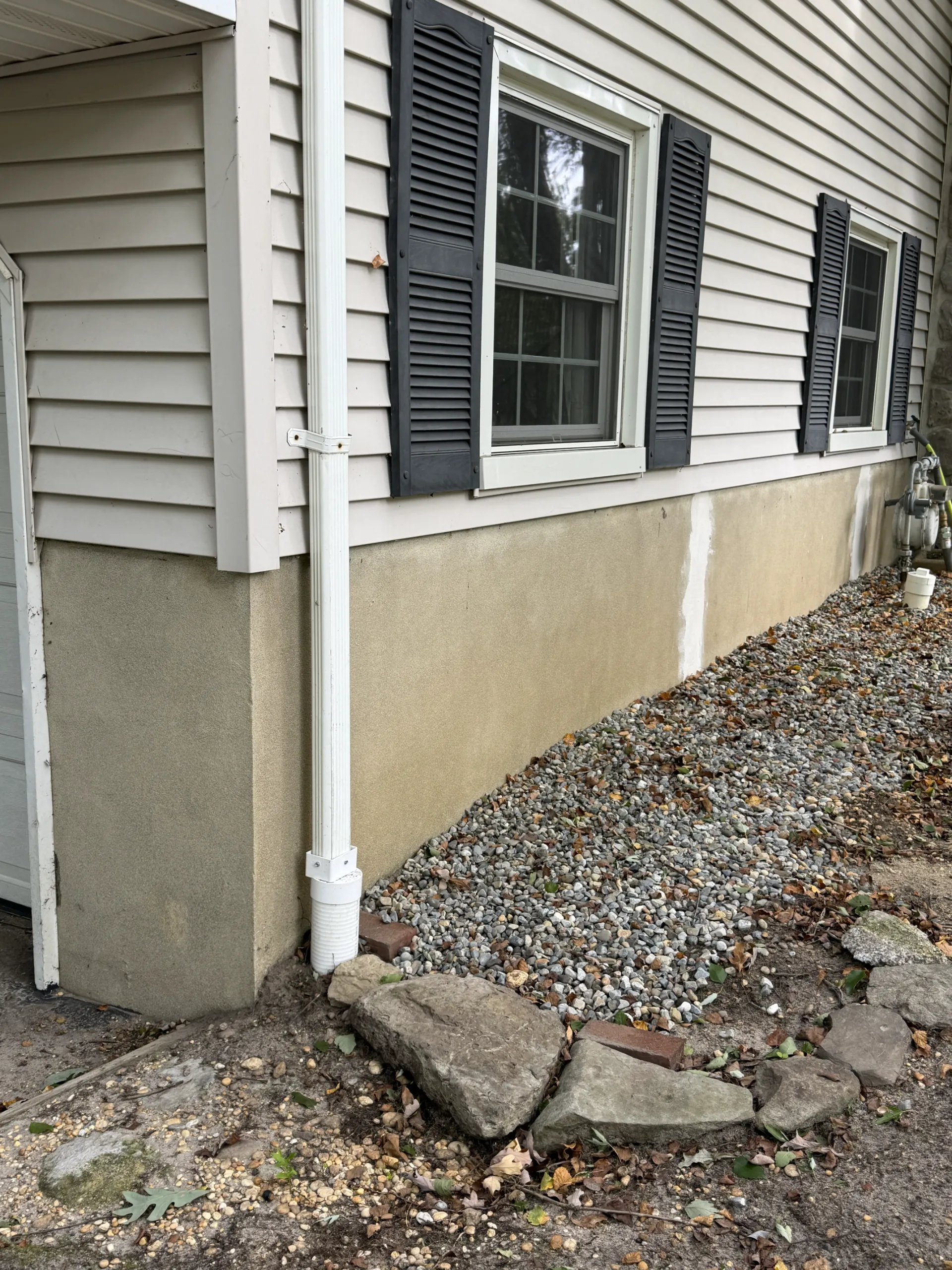 Before: the rendered foundation wall and patched corner beside the garage.