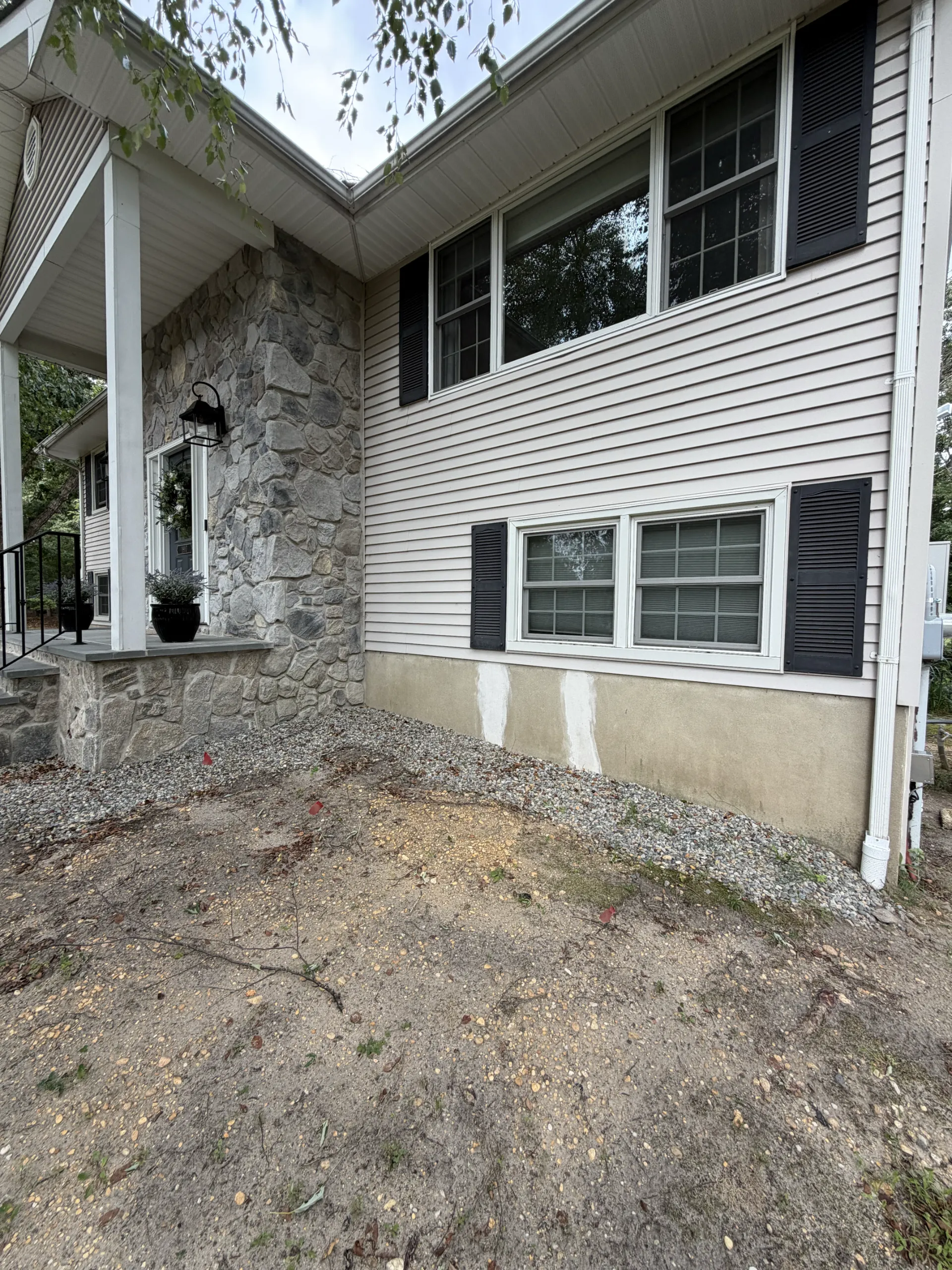 The same foundation wall with its original rendered finish and visible patches
