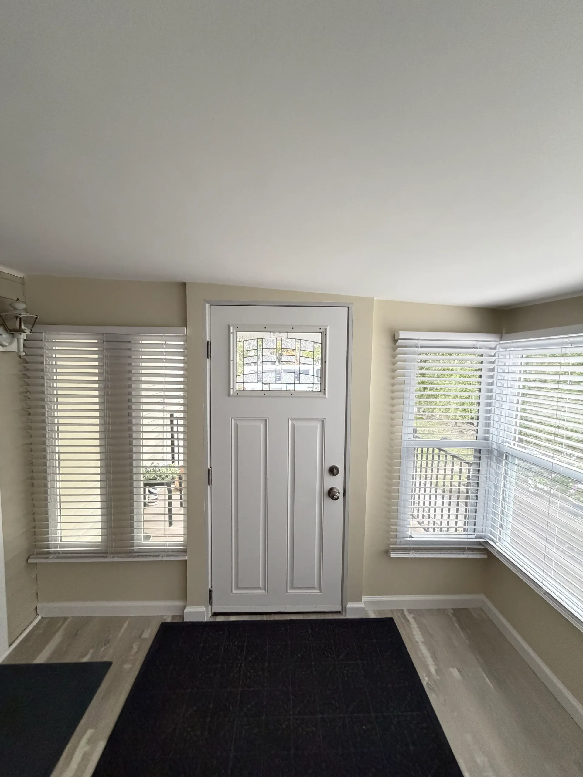 After: the entrance with a light neutral door, white casing and baseboards against the warm wall color.