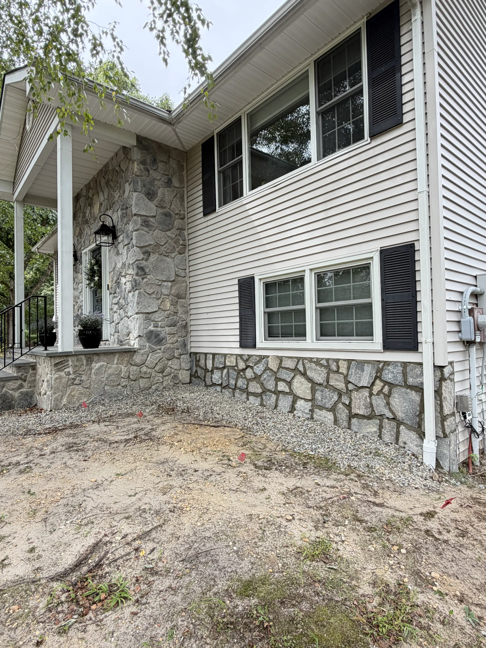 Stone facing installed along the exposed foundation wall beside the entrance