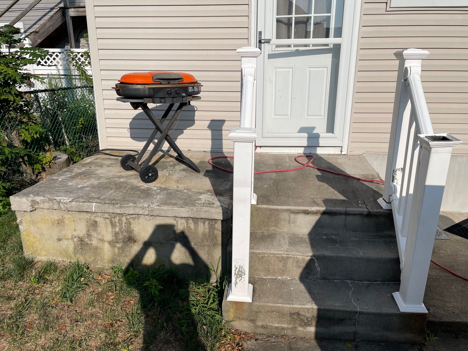 Before: the left entrance with a cracked landing, worn steps and the original white railing posts.