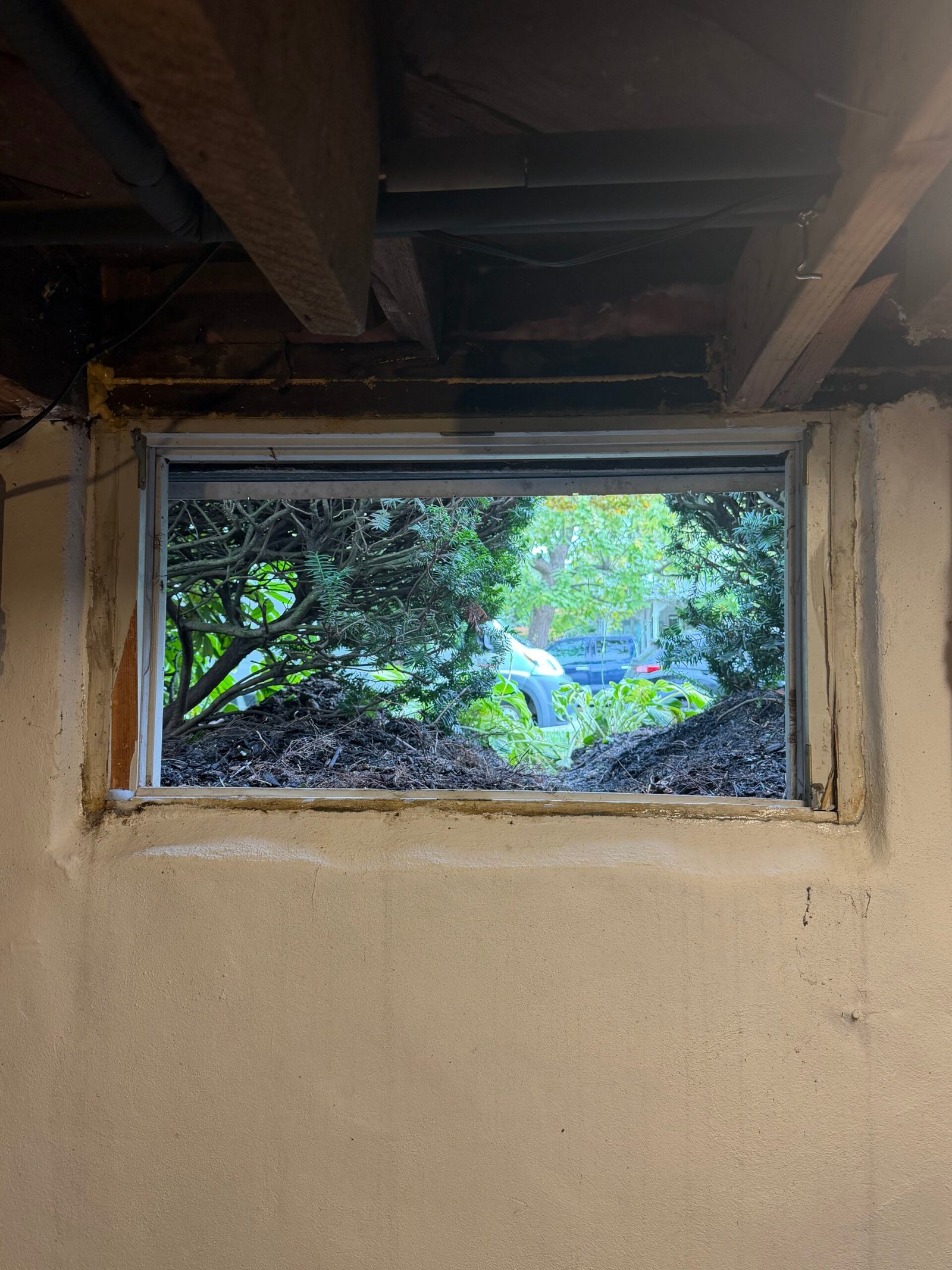 Before: the existing basement window and its surrounding wall opening beneath the ceiling joists.