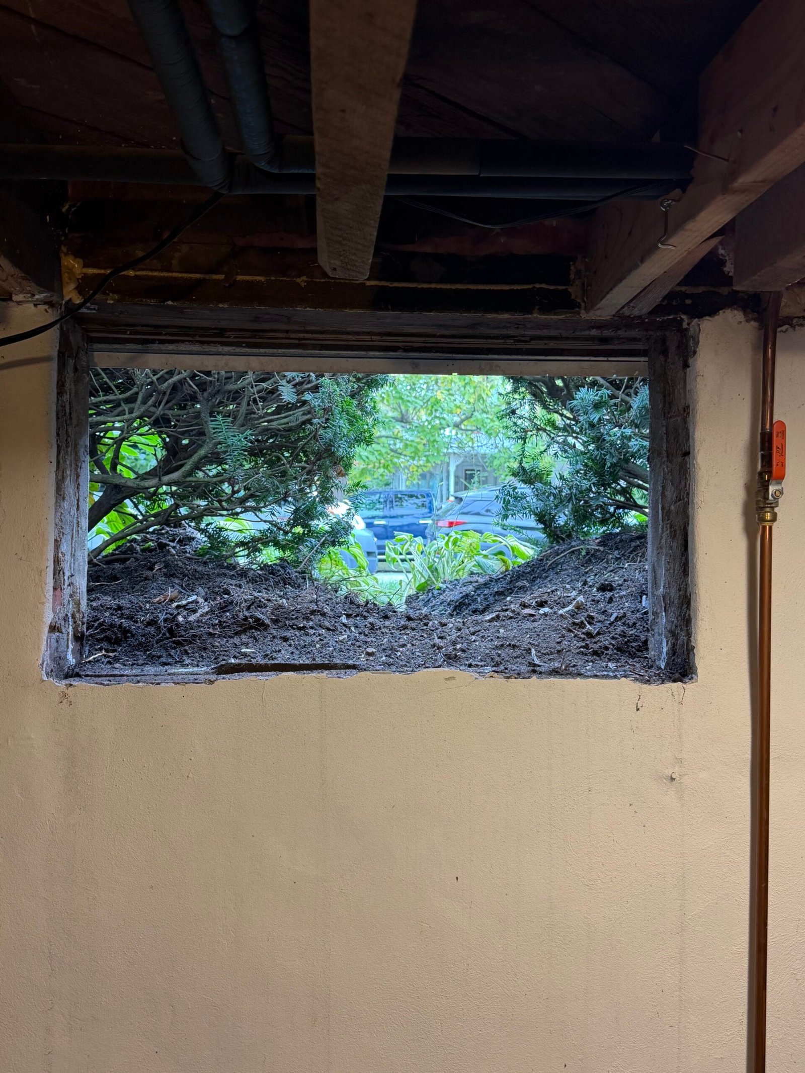 The old window removed, leaving the basement wall opening clear for the replacement.