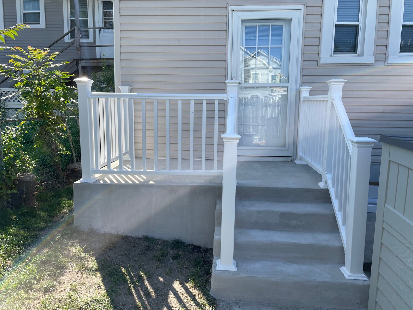 After: the rebuilt left porch and steps with white landing and stair railings.