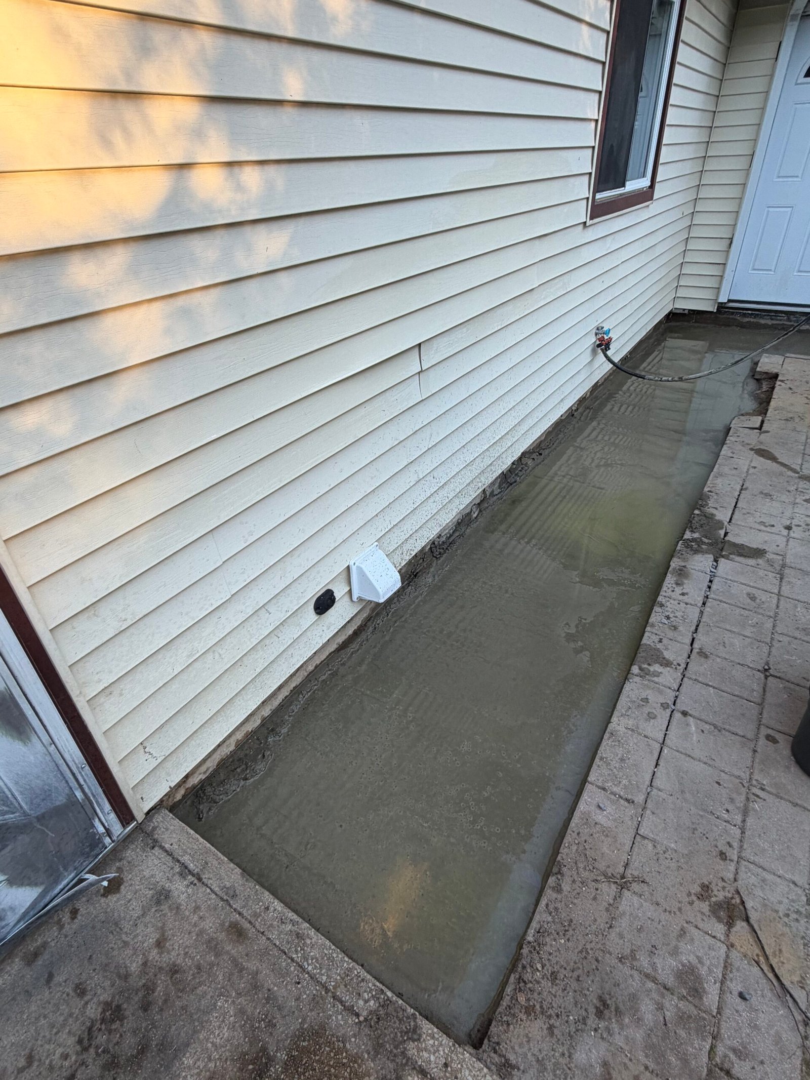New concrete placed and surface-finished along the house wall.