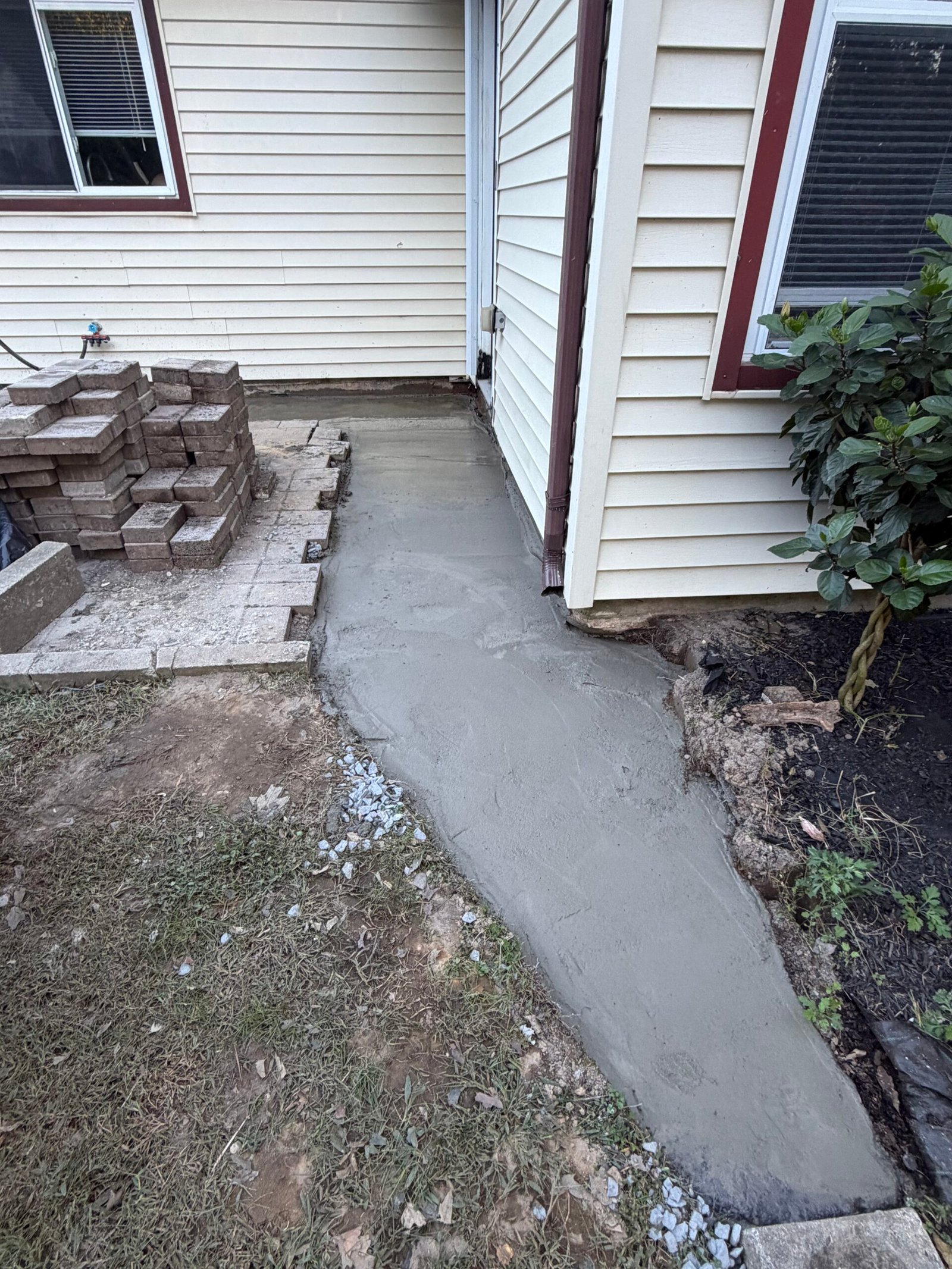 The concrete strip continuing around the entrance beside the retained paving.