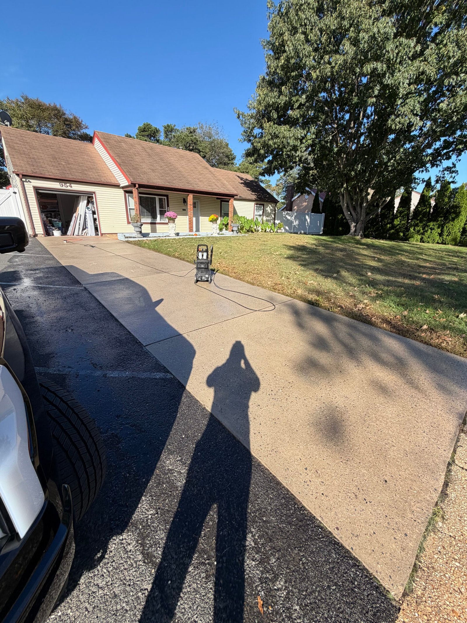 Before: the existing concrete driveway strip beside the asphalt, with cleaning equipment on site.