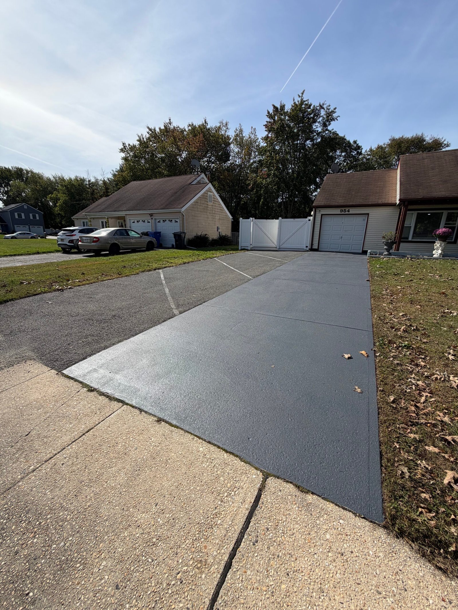 After: a full view of the coated concrete driveway strip toward the garage.