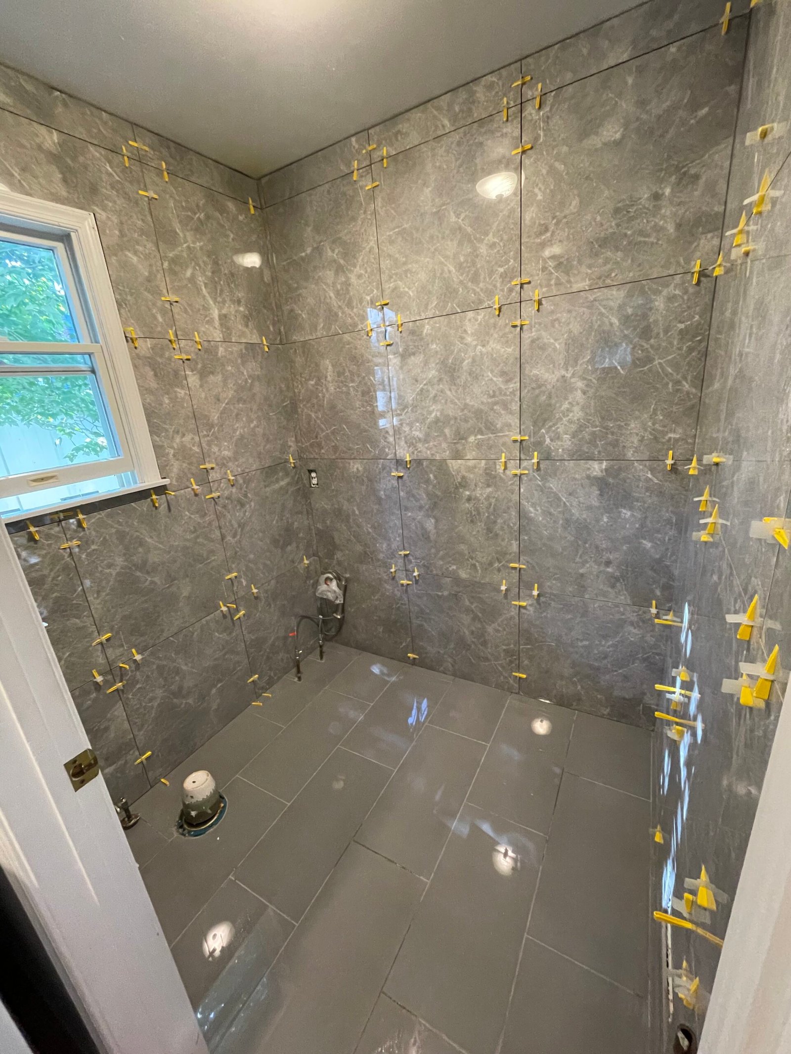 Wall tile carried around the window-side corner while installation continued.