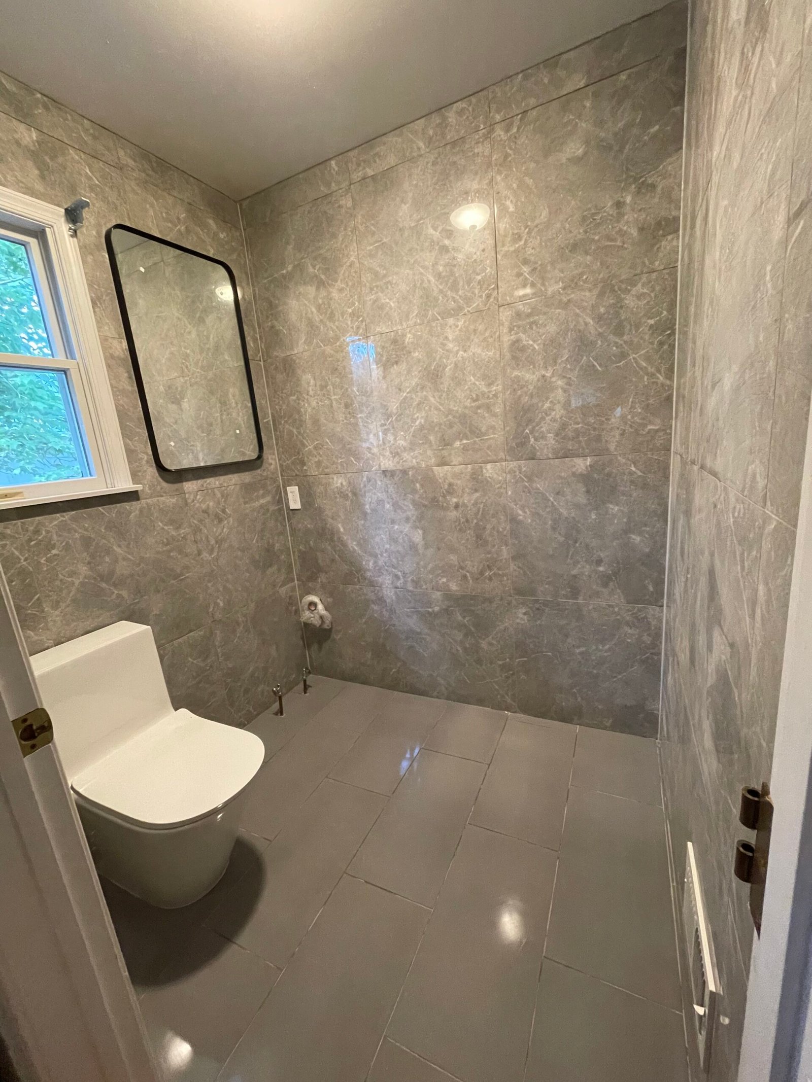 The toilet and black-framed mirror in place before the vanity was fitted.