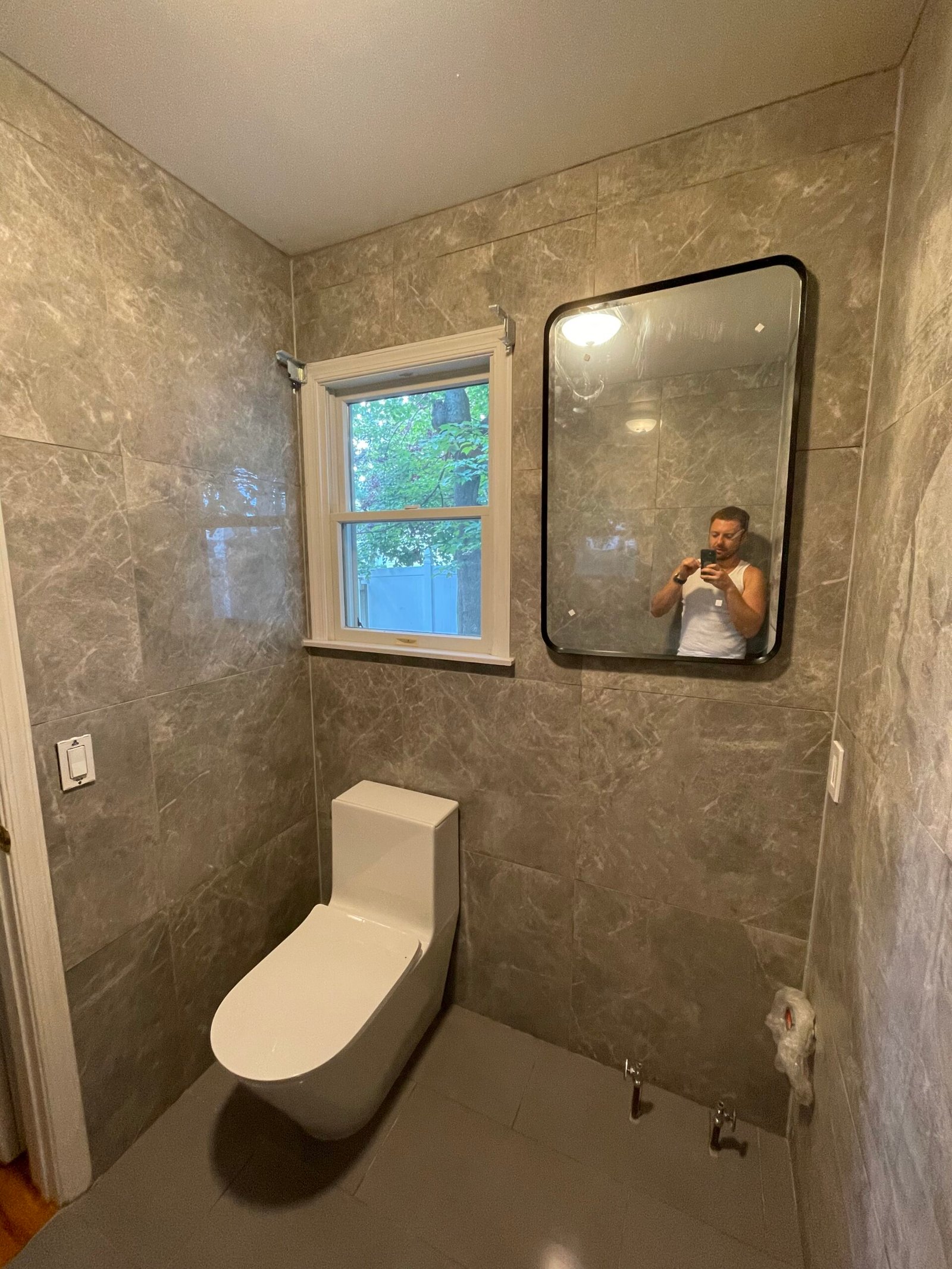 The tiled room with the toilet installed and vanity plumbing still exposed.