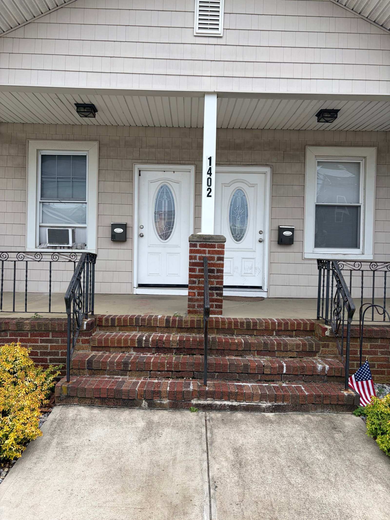 Before: the original brick entry stairs and central porch pier, viewed from the front.