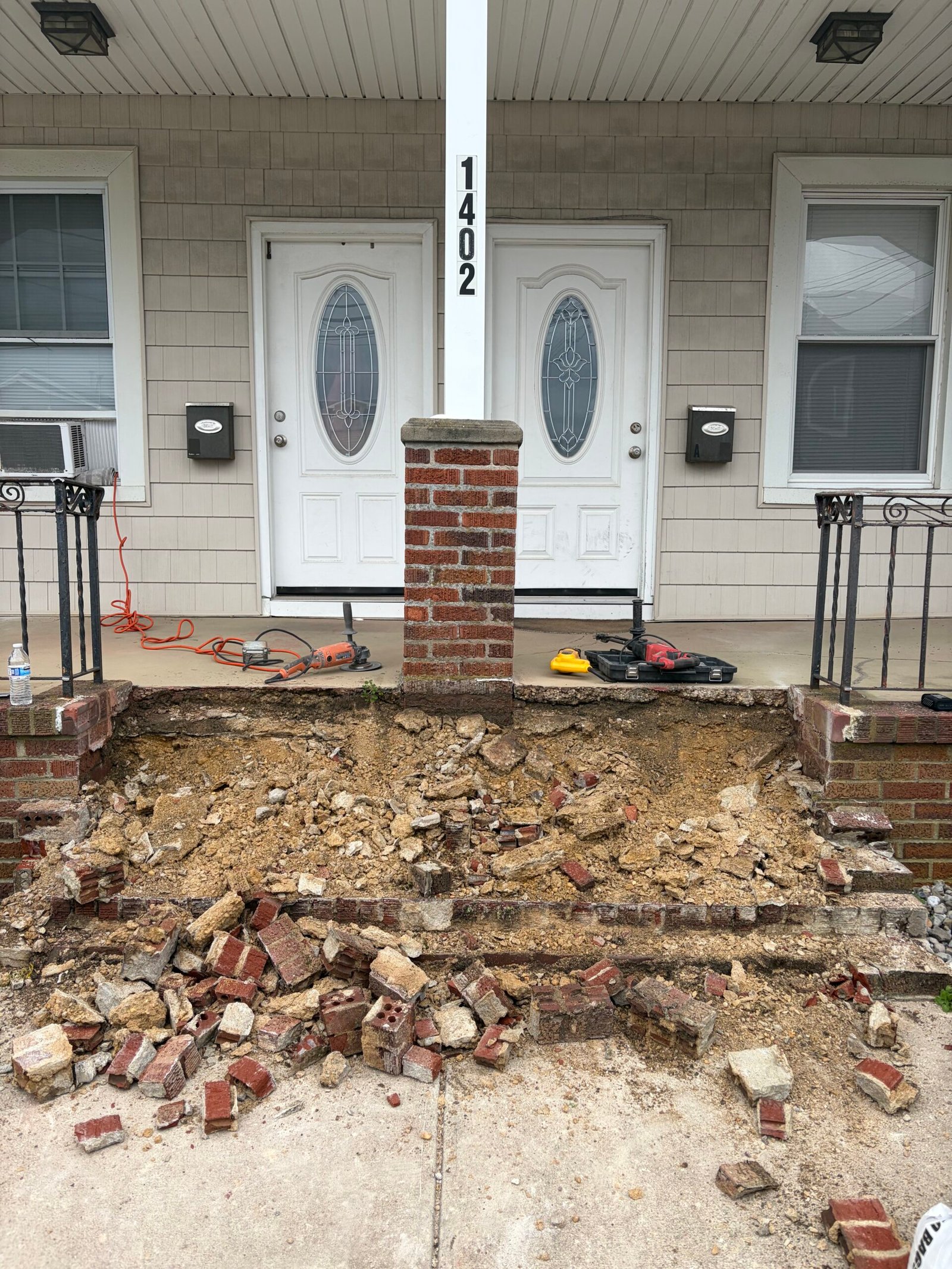 The old entry stairs being removed, with the opened stair area and brick debris visible.