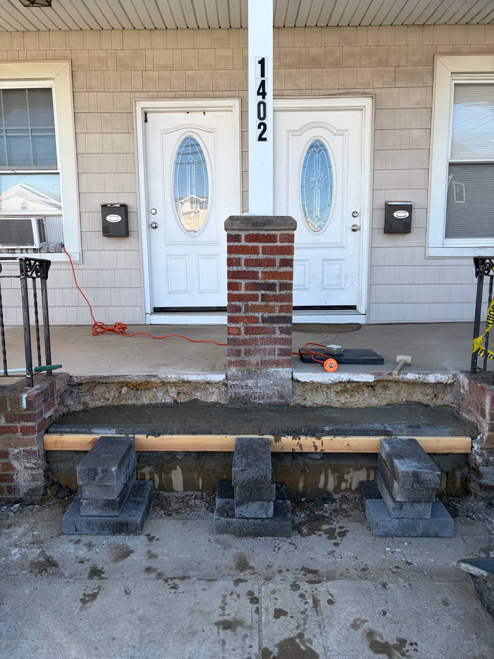 The first gray tread during installation, with masonry repairs and temporary work supports visible.