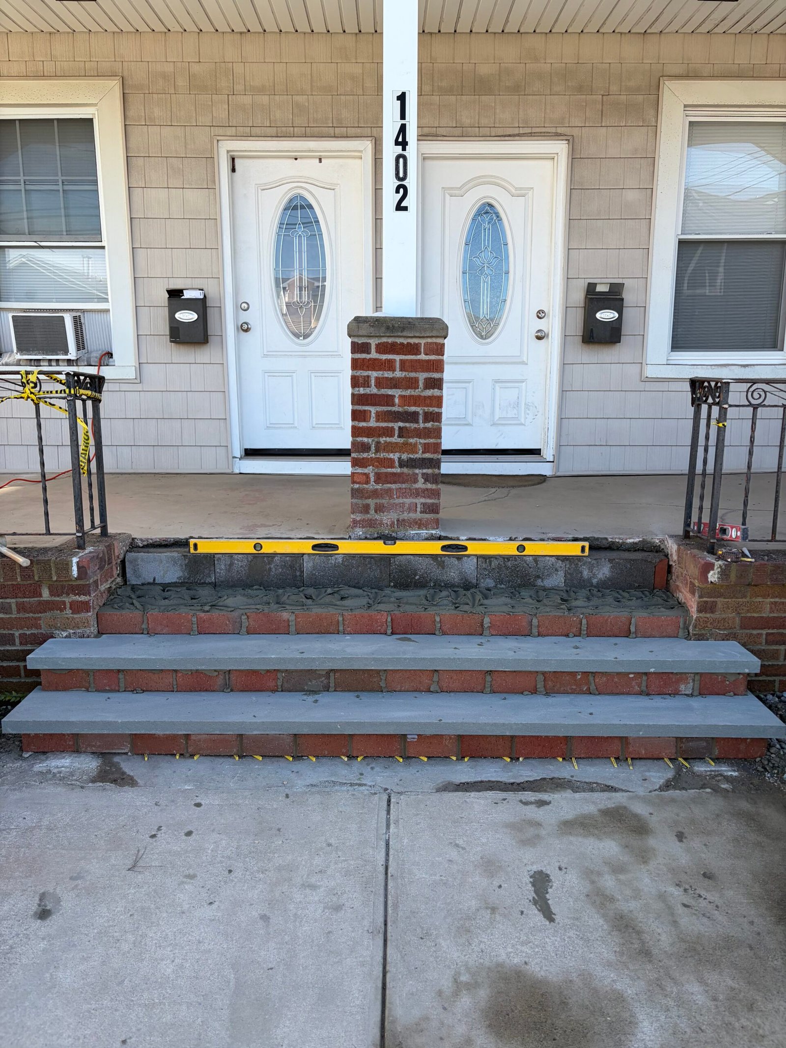 The gray treads aligned across the rebuilt entry stairs before handrails and final finishes.