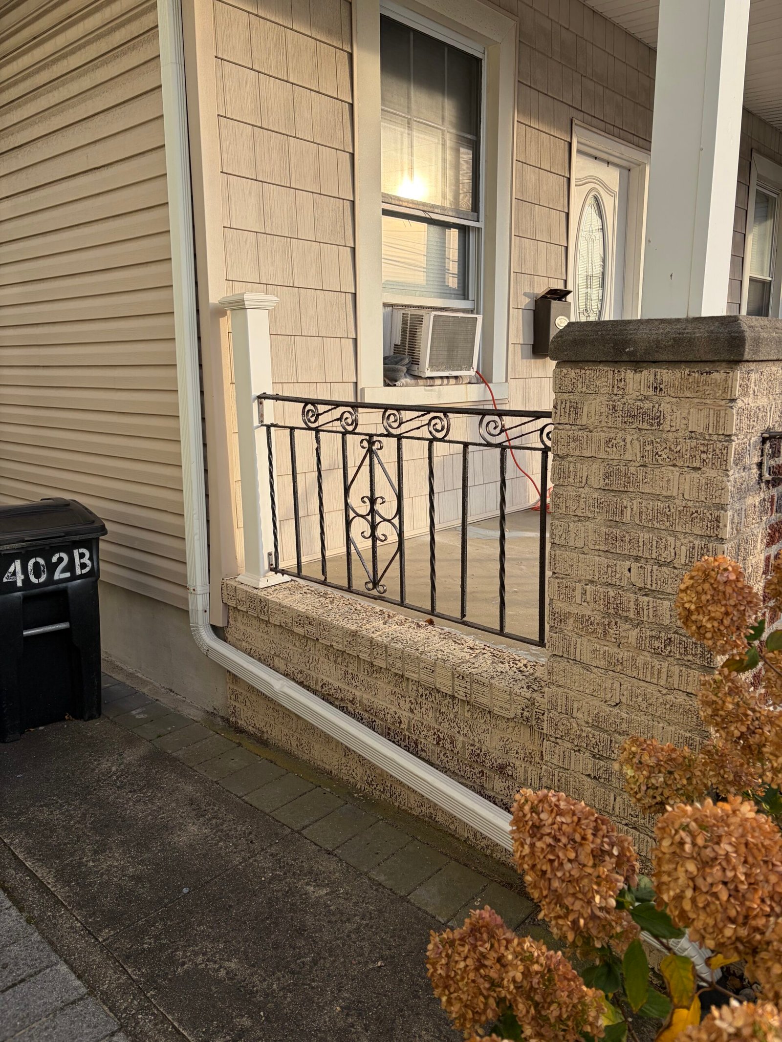 The light finish on a porch pier and side wall beside the retained black railing.