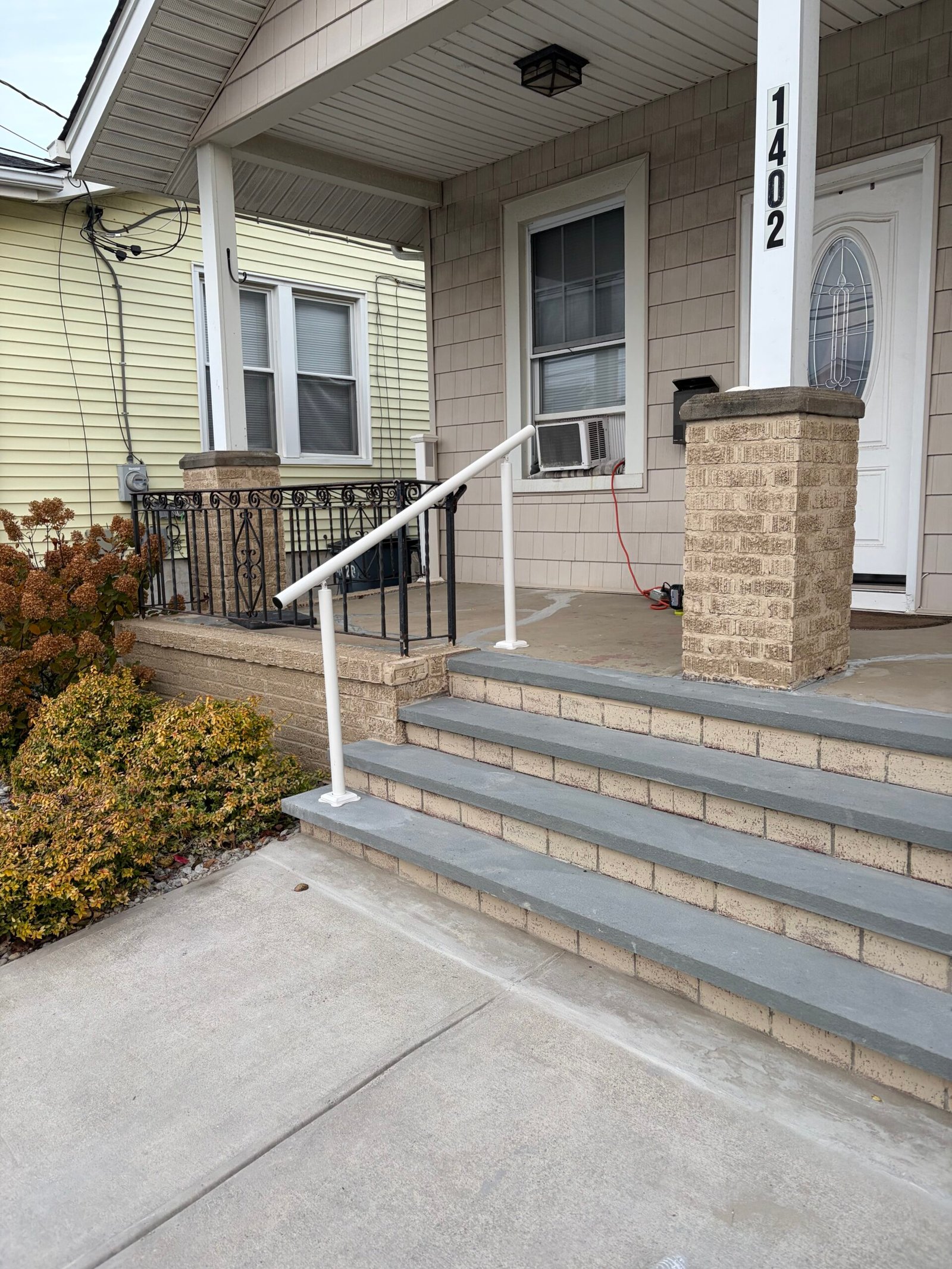 After: the entry stairs with gray treads, white handrails and a coordinated light masonry finish.