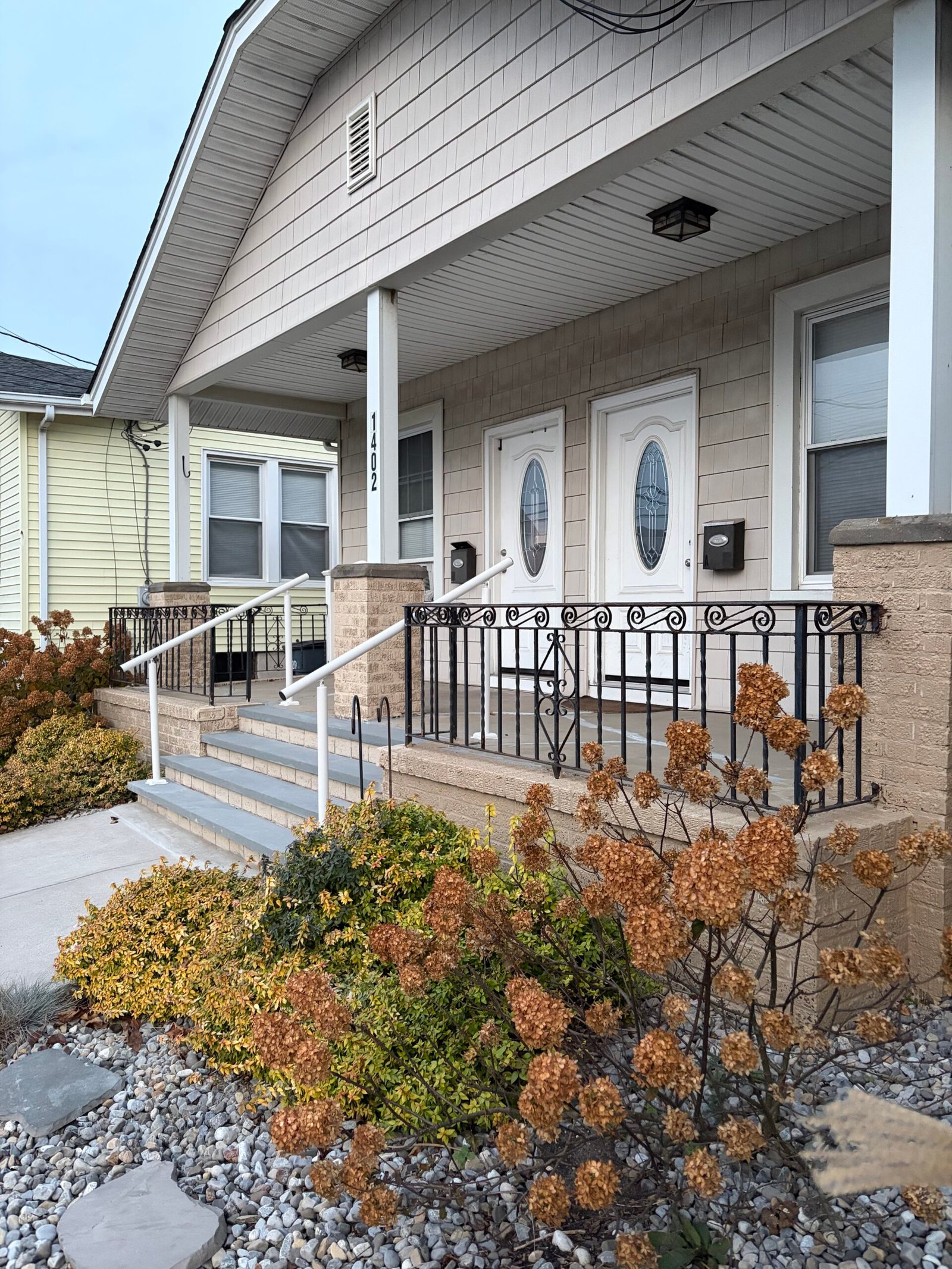 After: the renovated porch and stairs from the garden side, with black railings retained.
