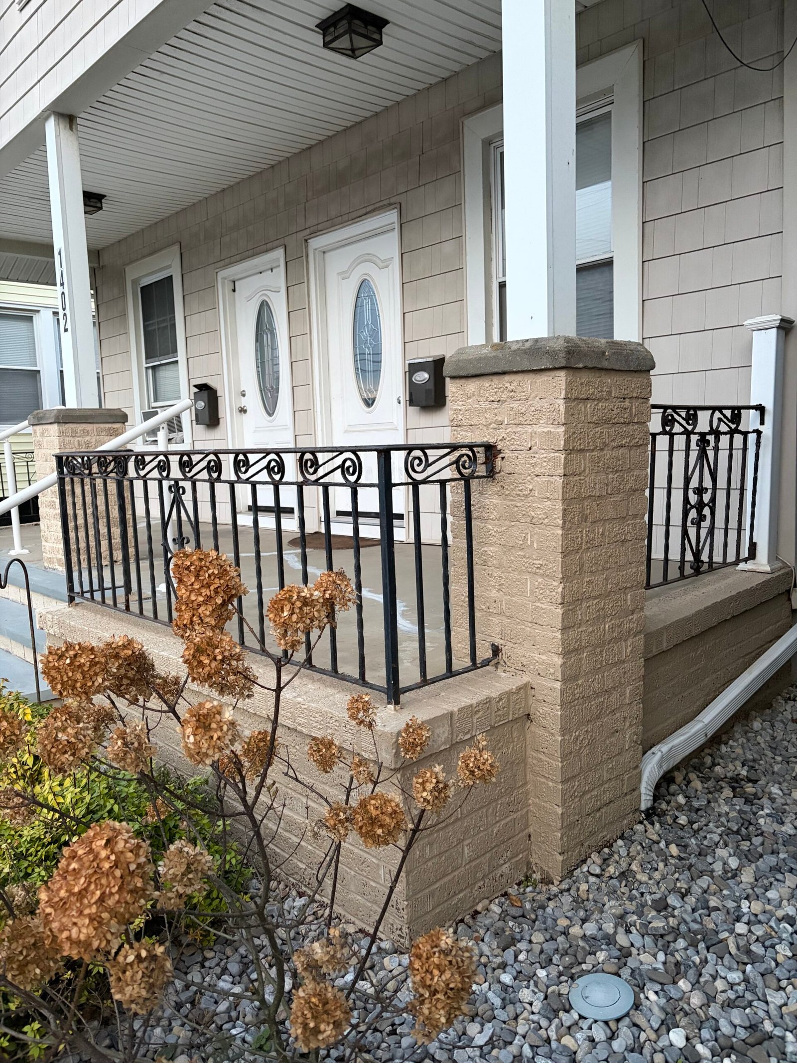 After: the finished porch corner, masonry base and pier beneath the existing black railing.
