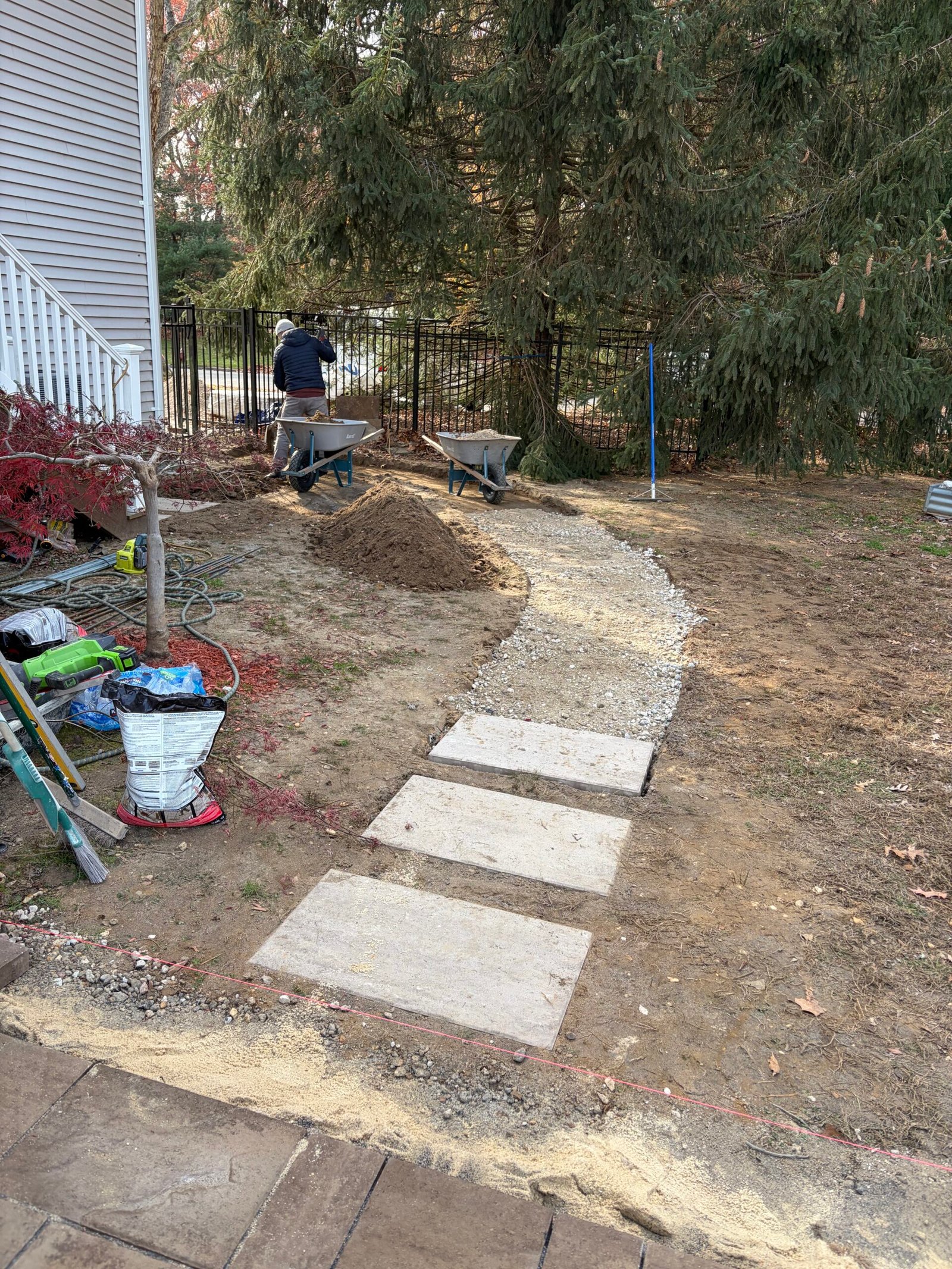 Granular material following the side-yard curve, with stepping stones near the stair landing.
