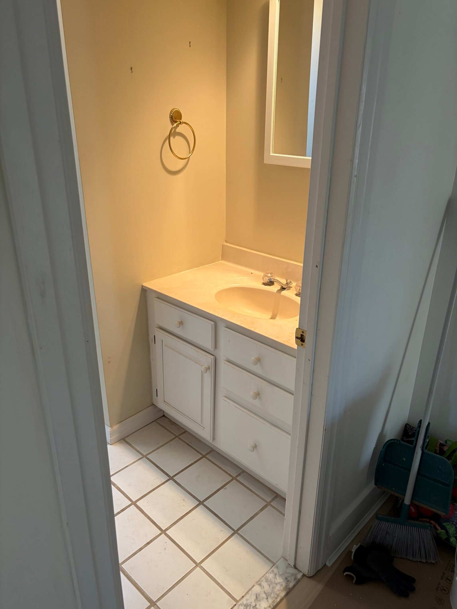 Before: the existing vanity, sink, mirror and bathroom floor.