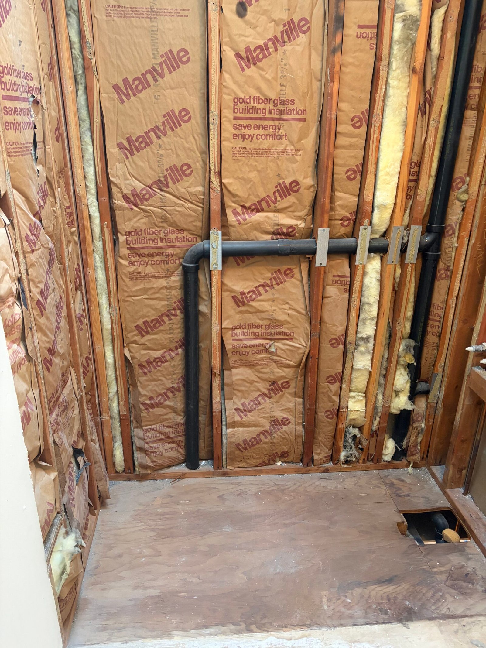 The former tub area opened to wall framing, insulation and plumbing.