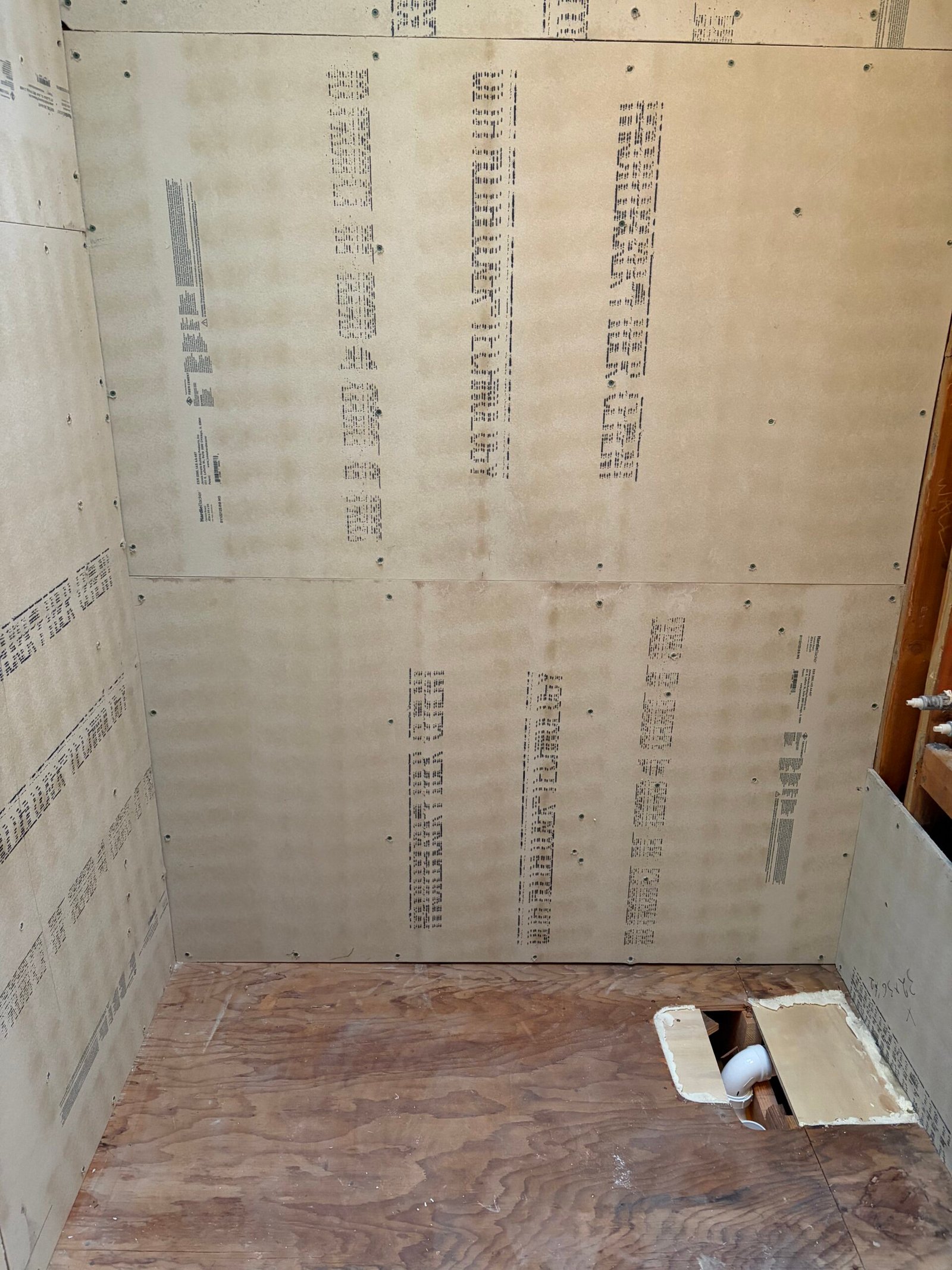 New backer boards enclosing the shower walls above the prepared subfloor.