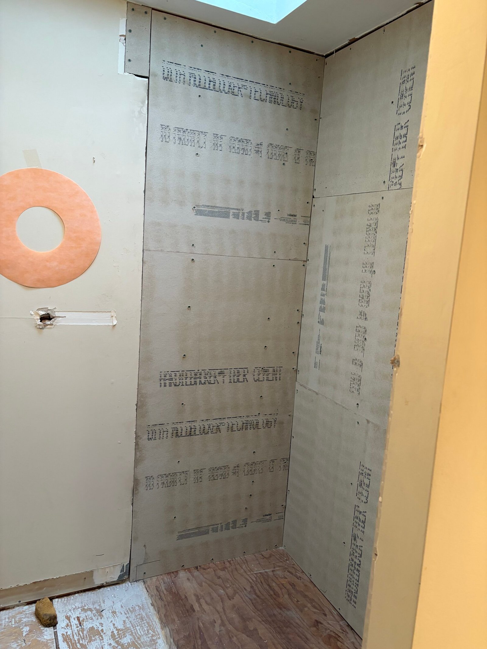 The shower wall boards and plumbing openings before seam treatment.