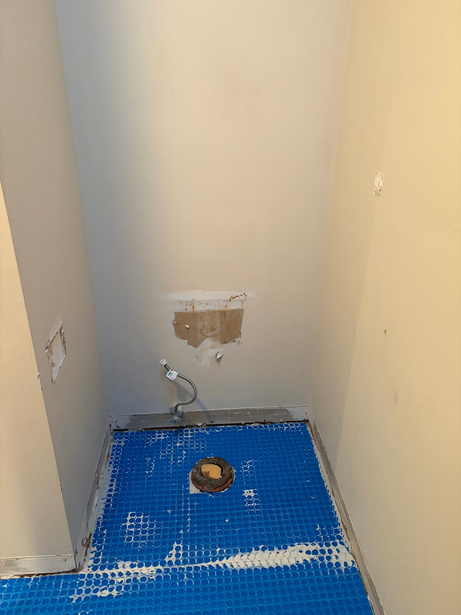 Blue floor underlayment installed in the toilet alcove.