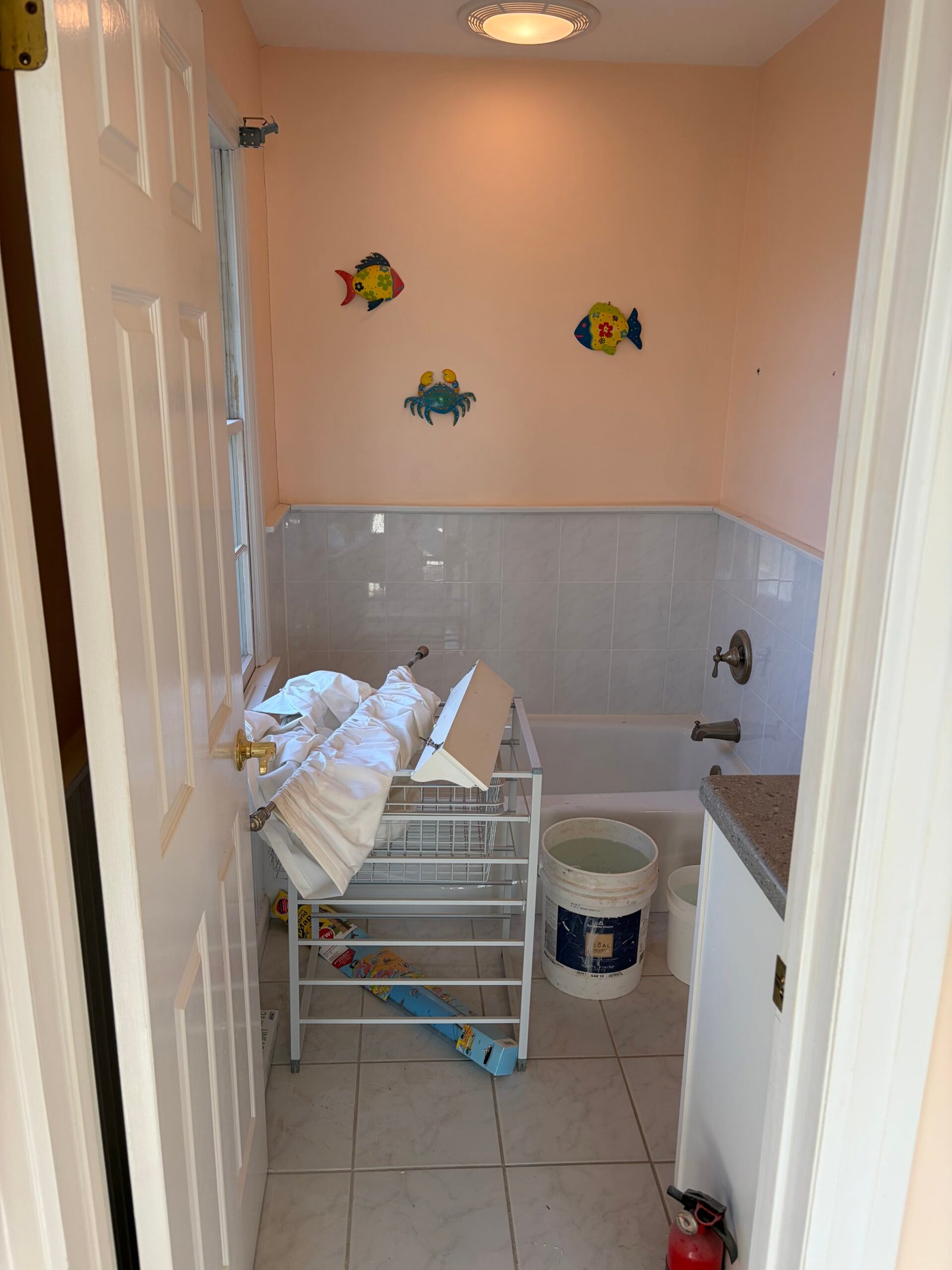 Before: the original peach-colored bathroom, bathtub area and tiled floor.