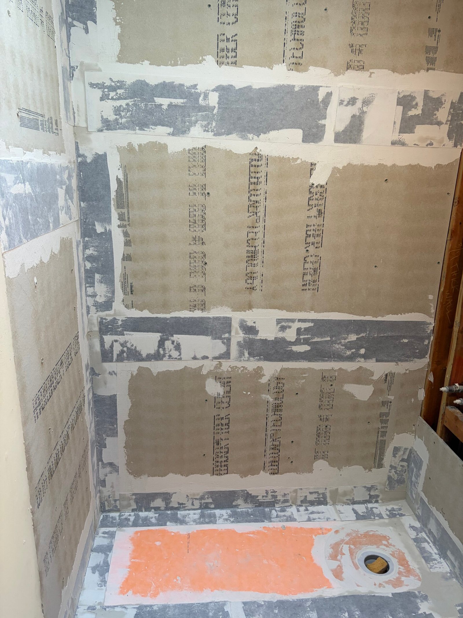 Shower-board joints and base edges treated before the wall coating.