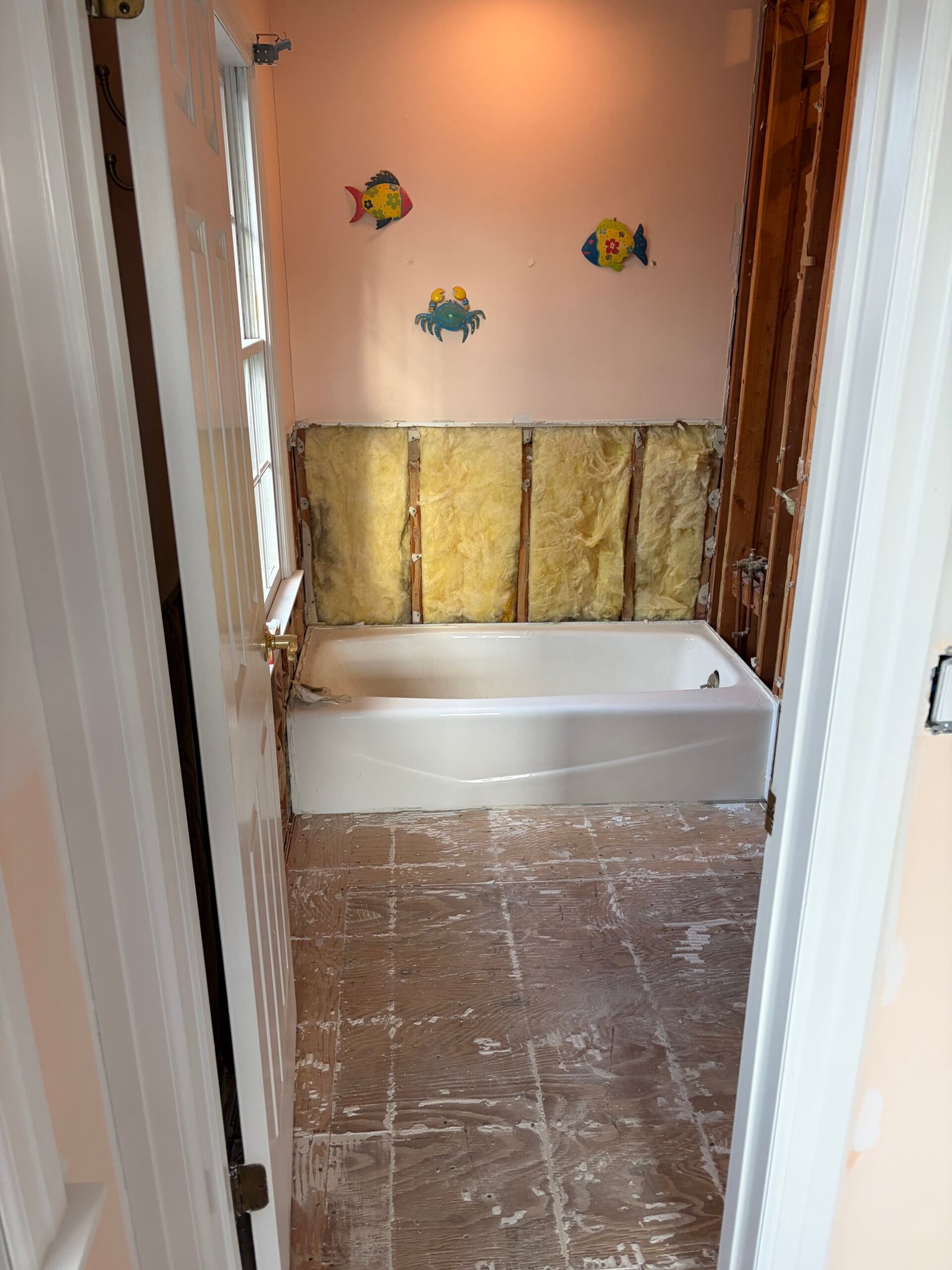 The old wall finishes and floor tile removed around the bathtub area.