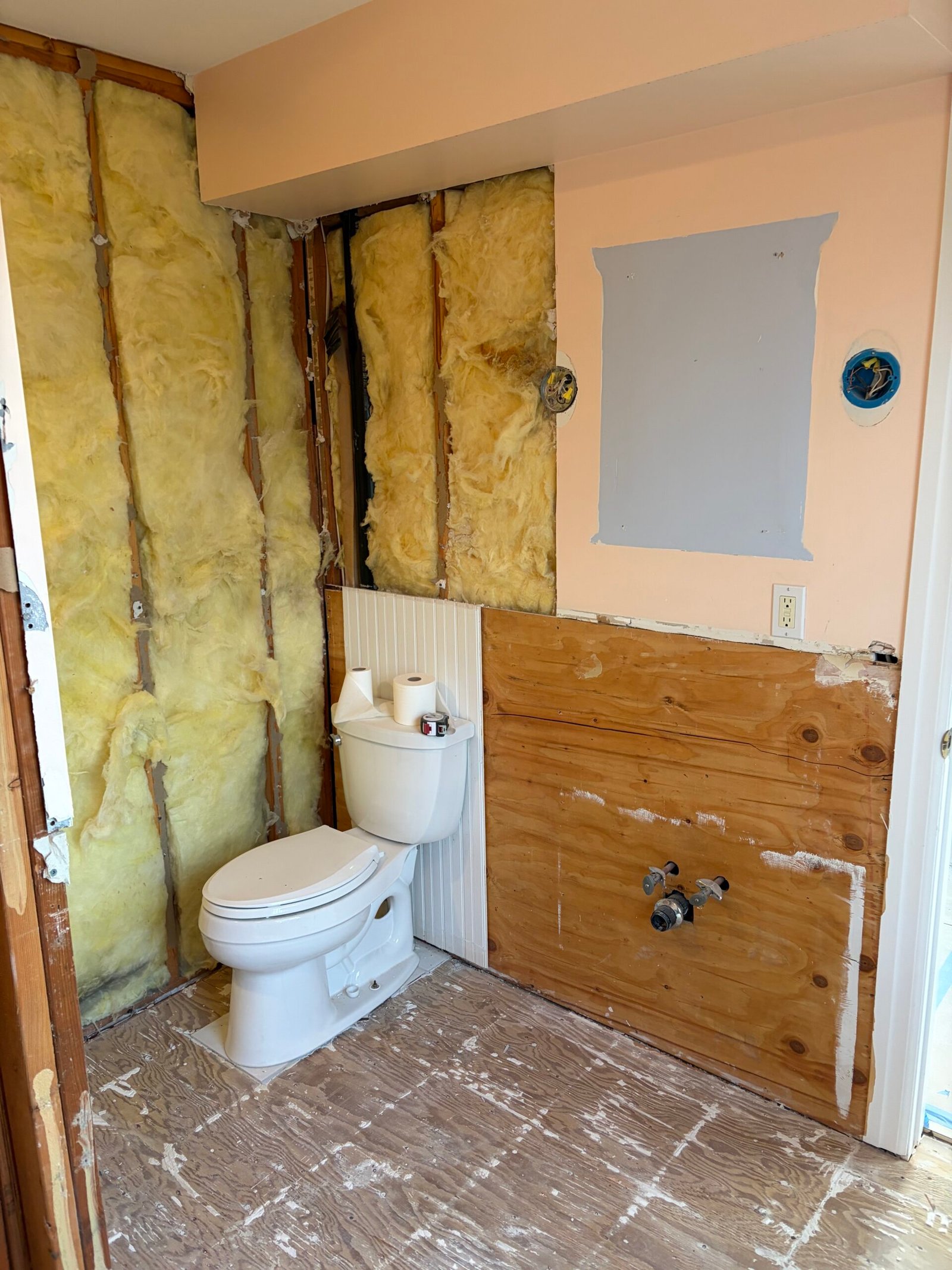The former vanity wall exposed, with the old fixtures being removed.