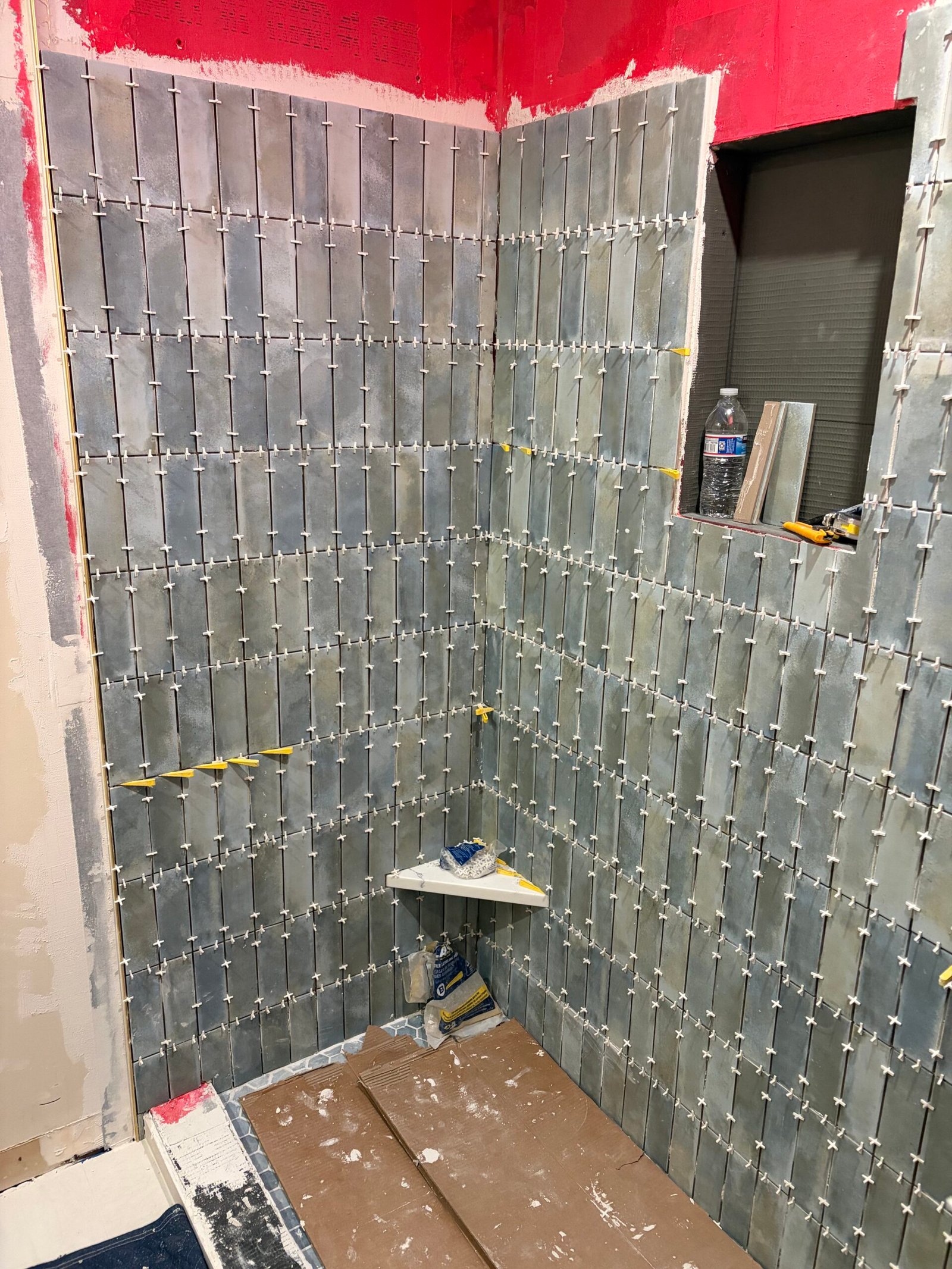 The niche wall and corner shelf while the vertical tile is being installed.