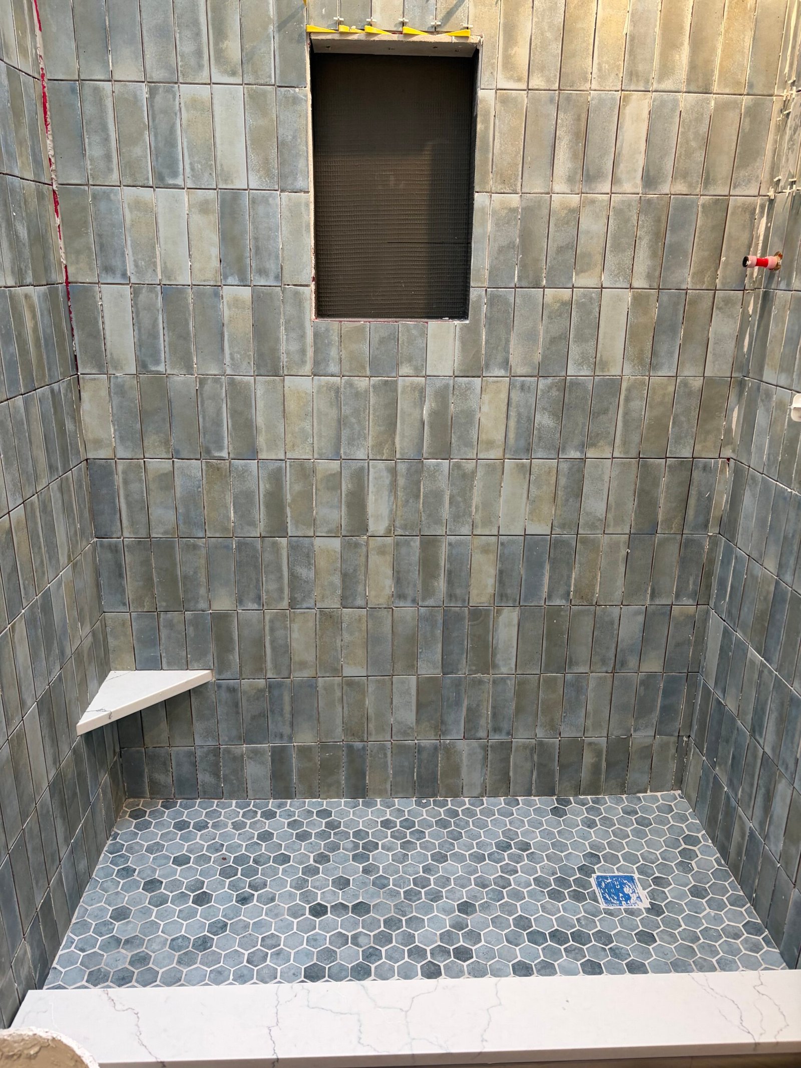 The tiled niche wall, corner shelf and hexagonal shower floor before final detailing.