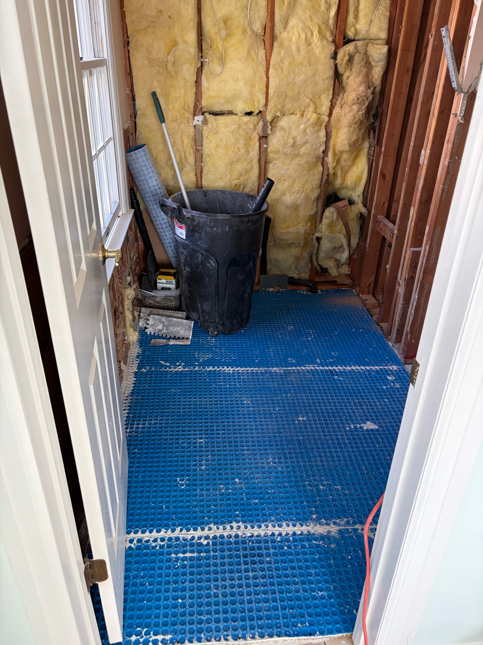 Blue floor underlayment fitted while the wall cavities remain open.