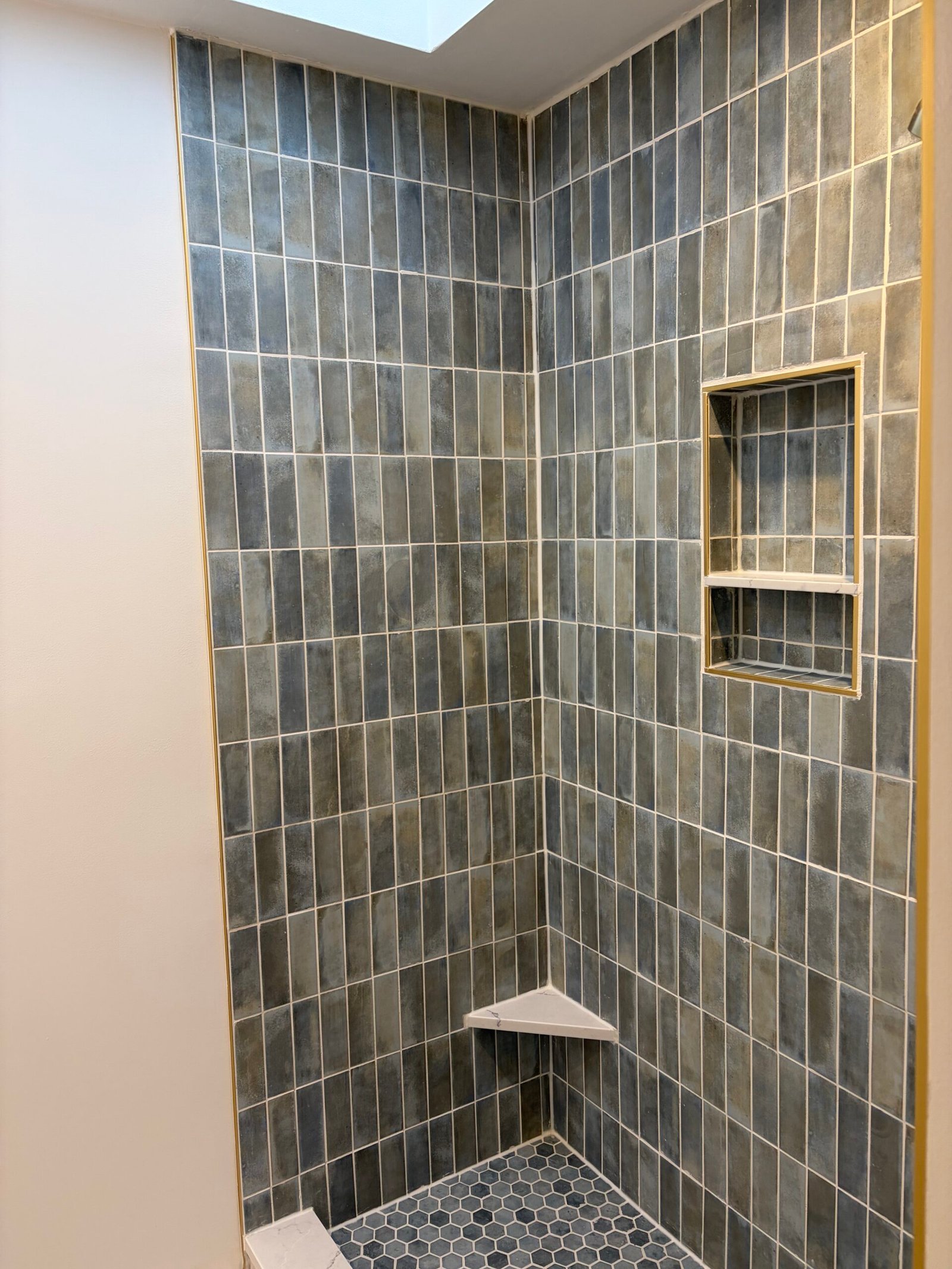 The grouted vertical shower tile, divided niche and corner shelf.