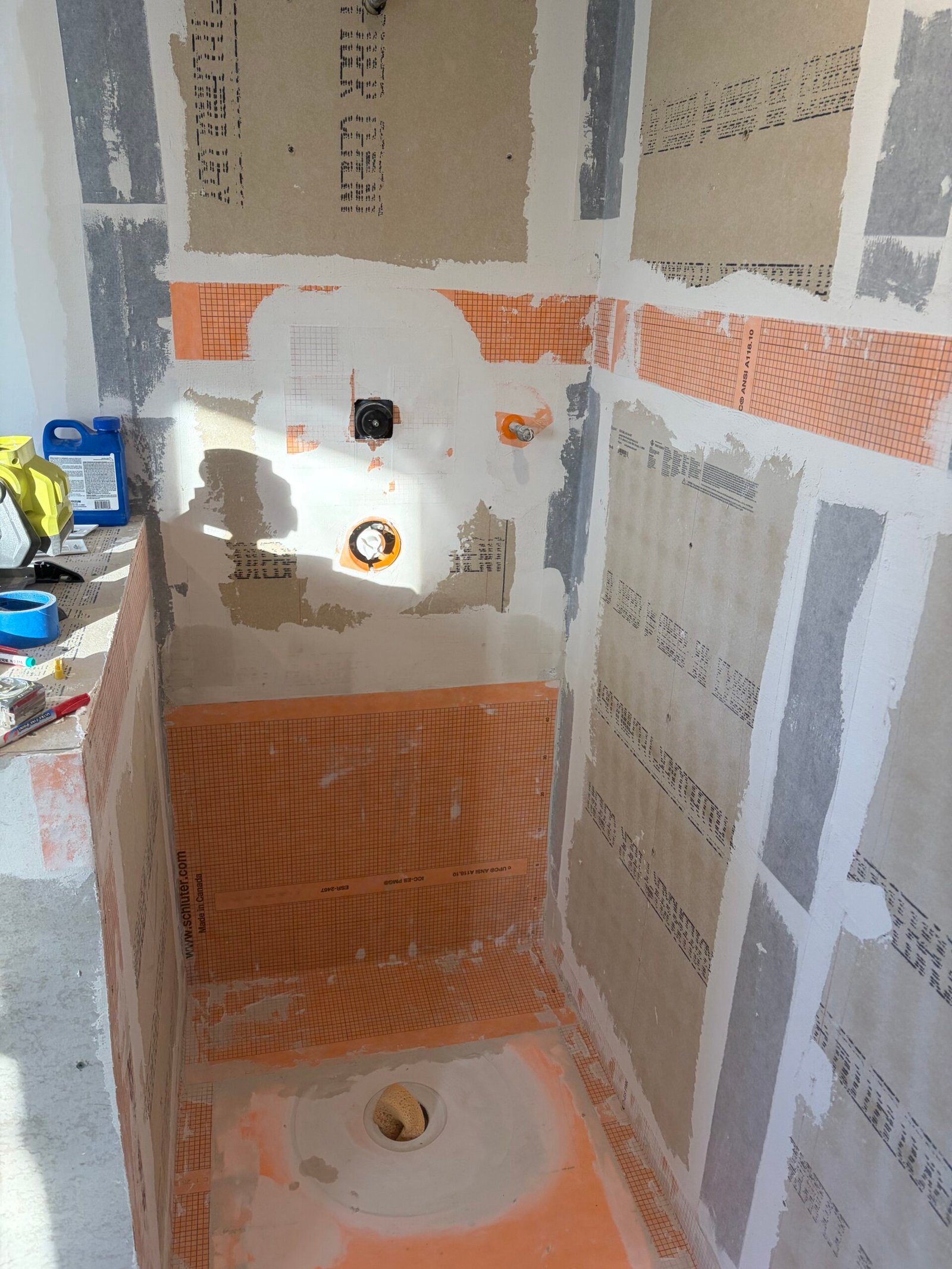 The shower base, wall-board joints and plumbing openings during preparation.