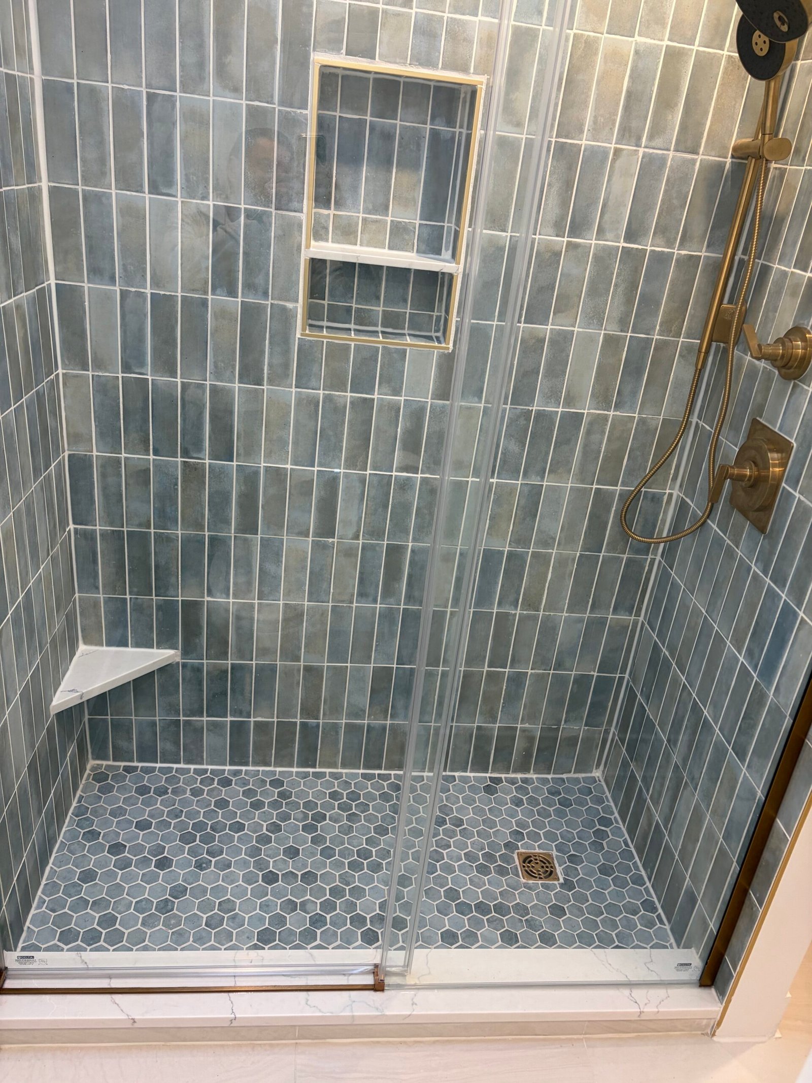 After: the glass enclosure, mosaic shower floor and finished threshold.