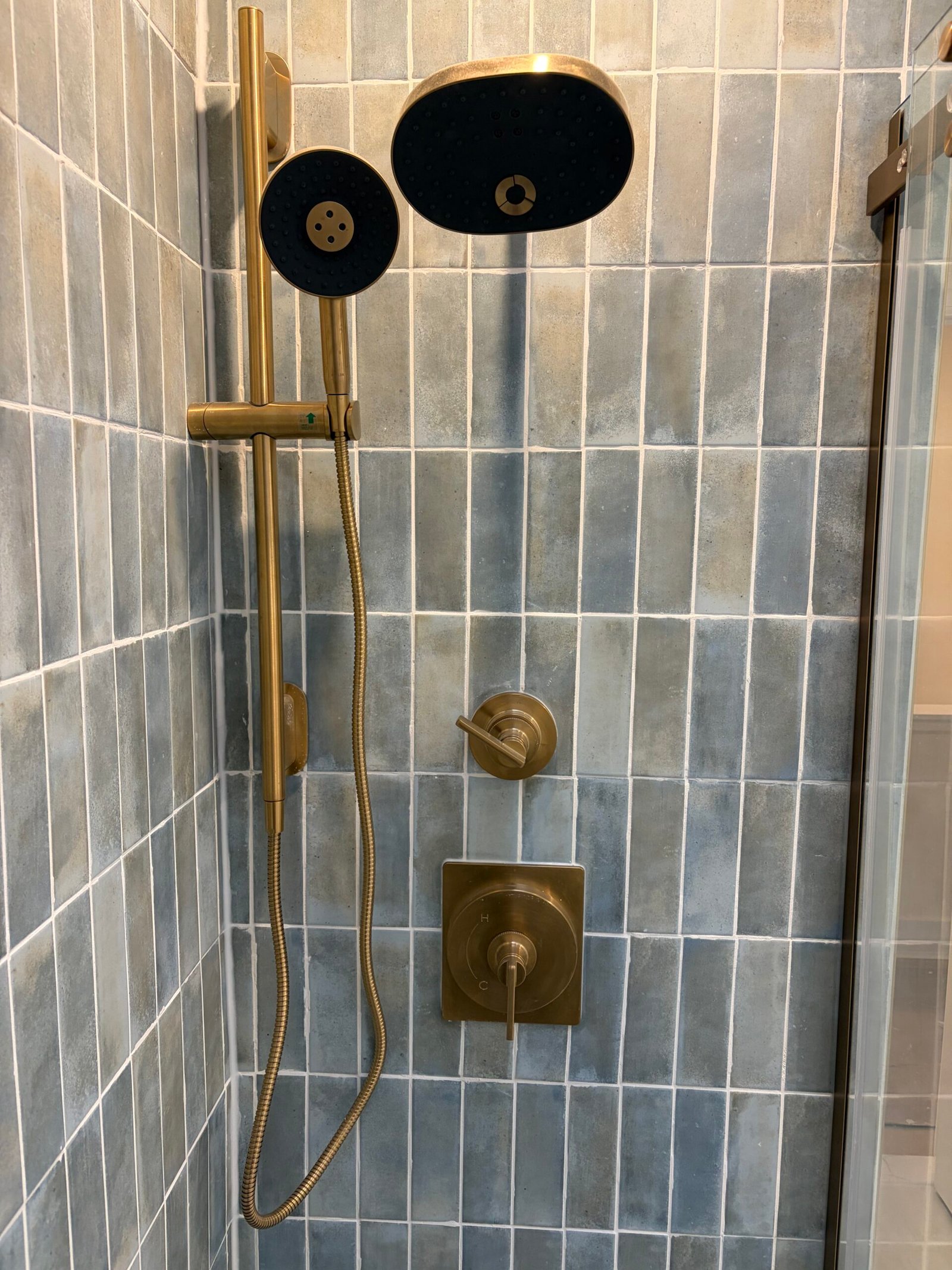 After: the showerhead, handheld shower and matching brass-tone controls.