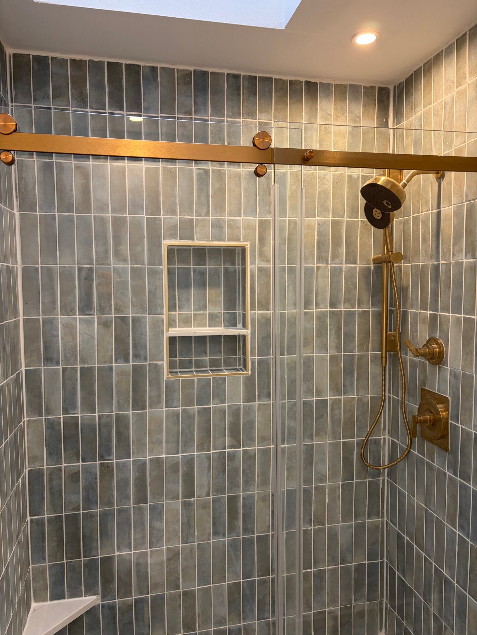 After: the tiled shower, recessed niche, glass doors and overhead light.