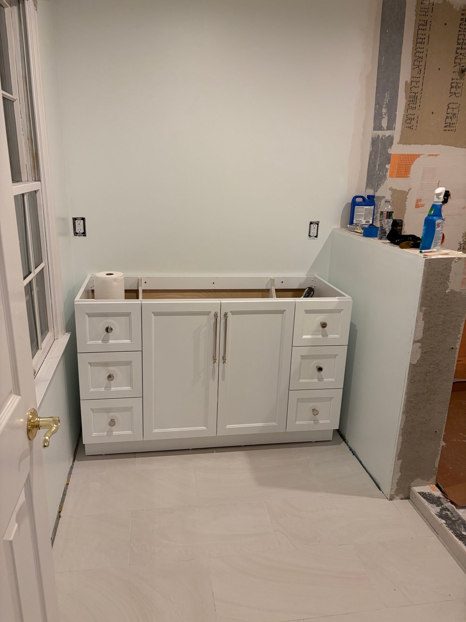 The white vanity cabinet positioned over the new light tile floor.