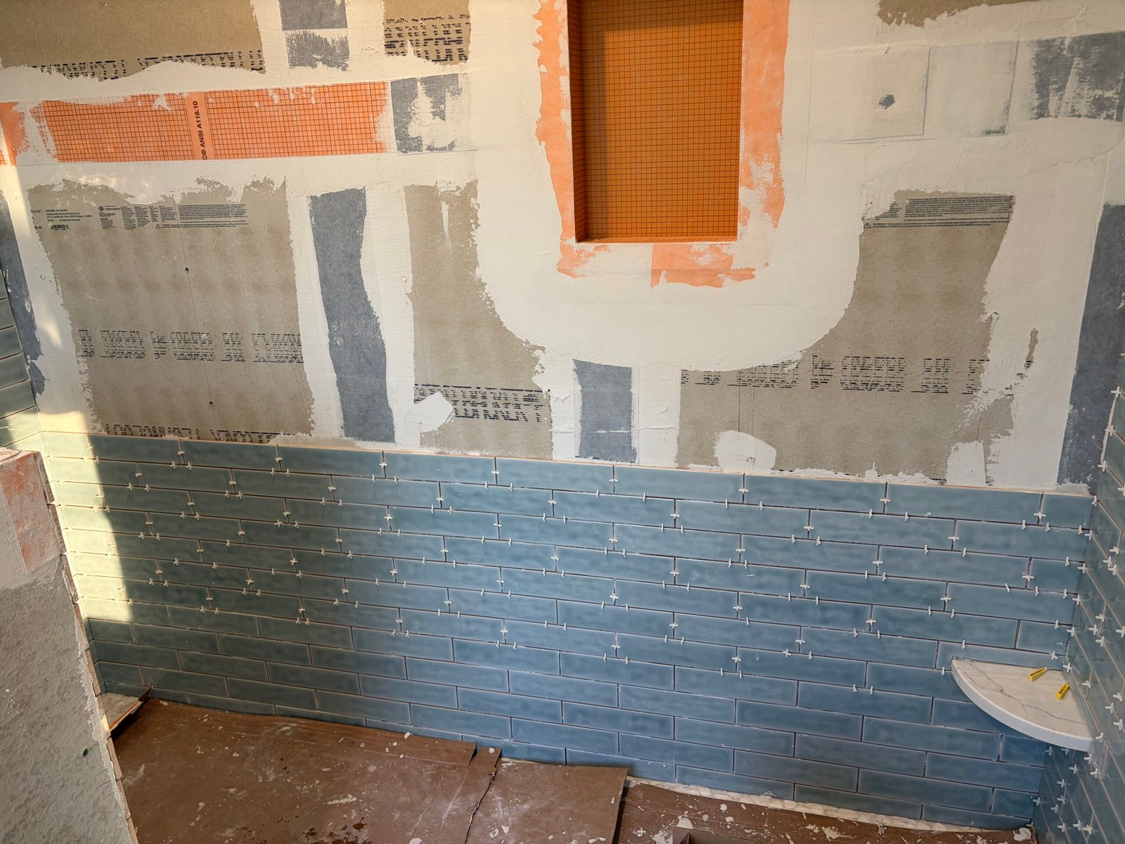 Blue shower tile progressing beneath the recessed niche.