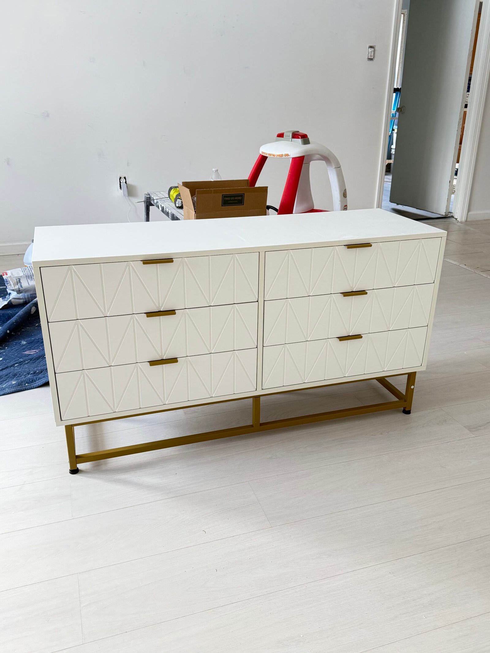 After: The completed white dresser with fitted drawers, gold-tone handles and a raised base.