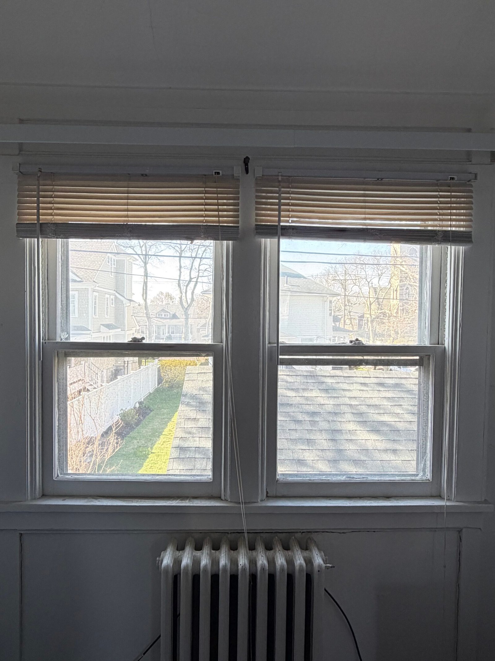 Before: the original paired windows and blinds above another radiator.