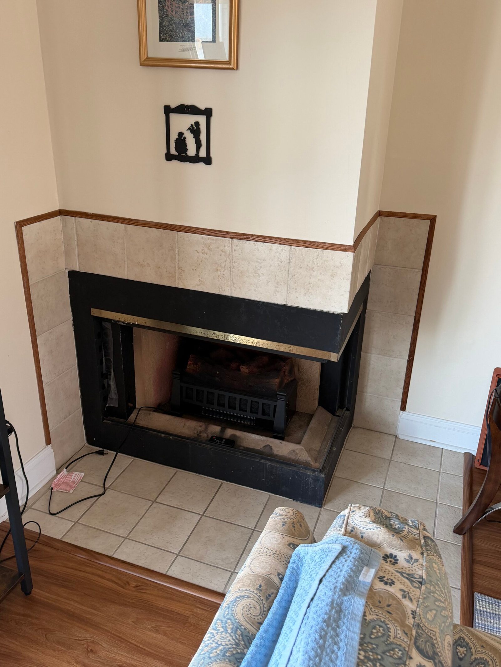 Before: the corner fireplace with its original black surround, light tile and narrow wood edging.
