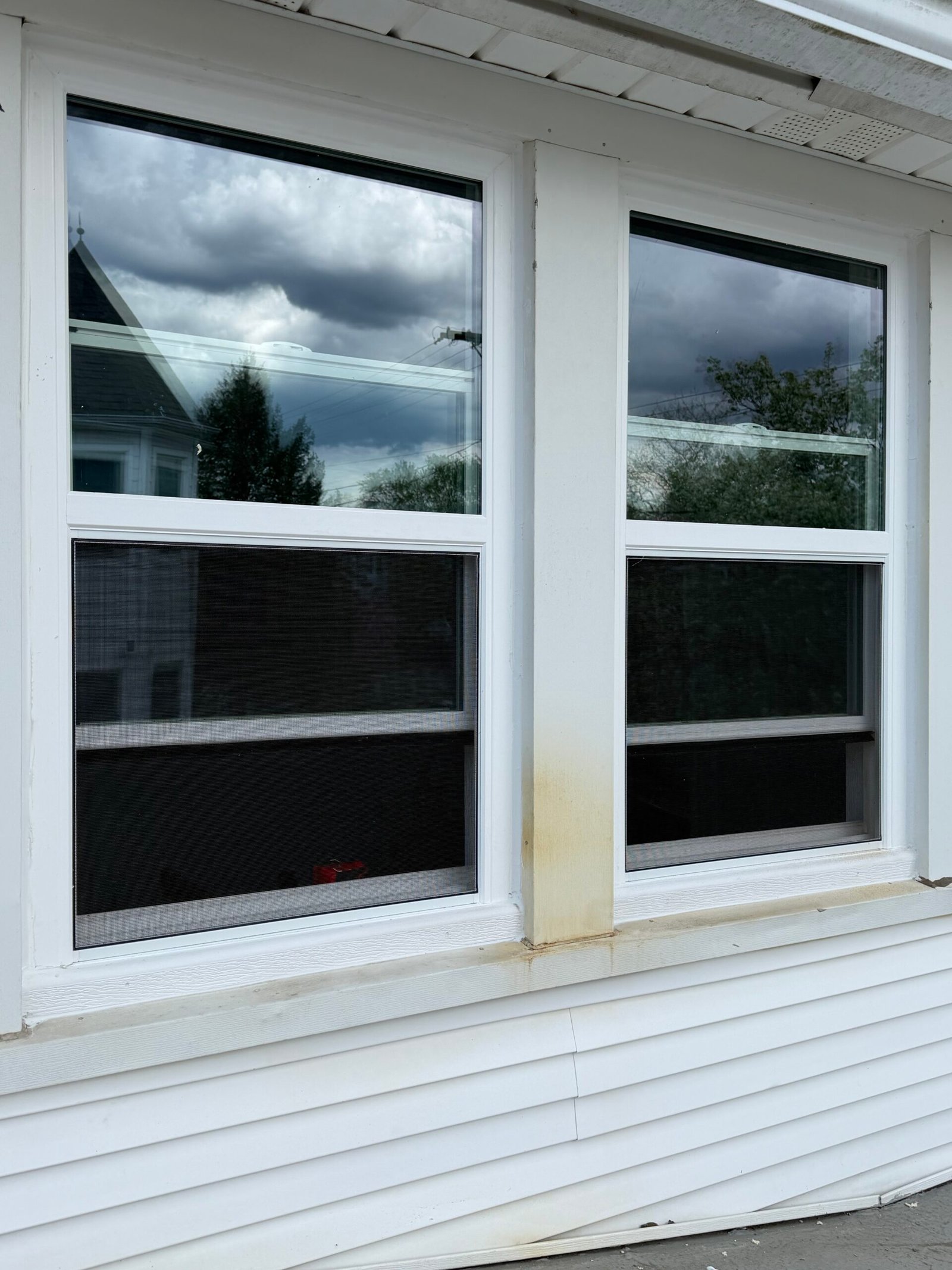 After: the paired replacement windows viewed from outside within the white exterior finish.
